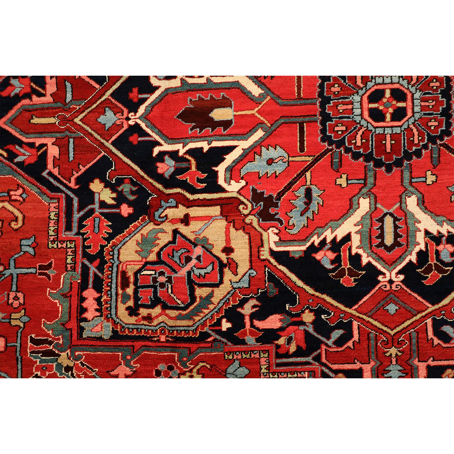 This antique Heriz Persian carpet circa 1910 in pure wool and vegetable dyes consists of a hand-knotted pile using a Persian knot upon a cotton warp and weft. The carpet features a stylized floral geometric medallion with an intricate border and