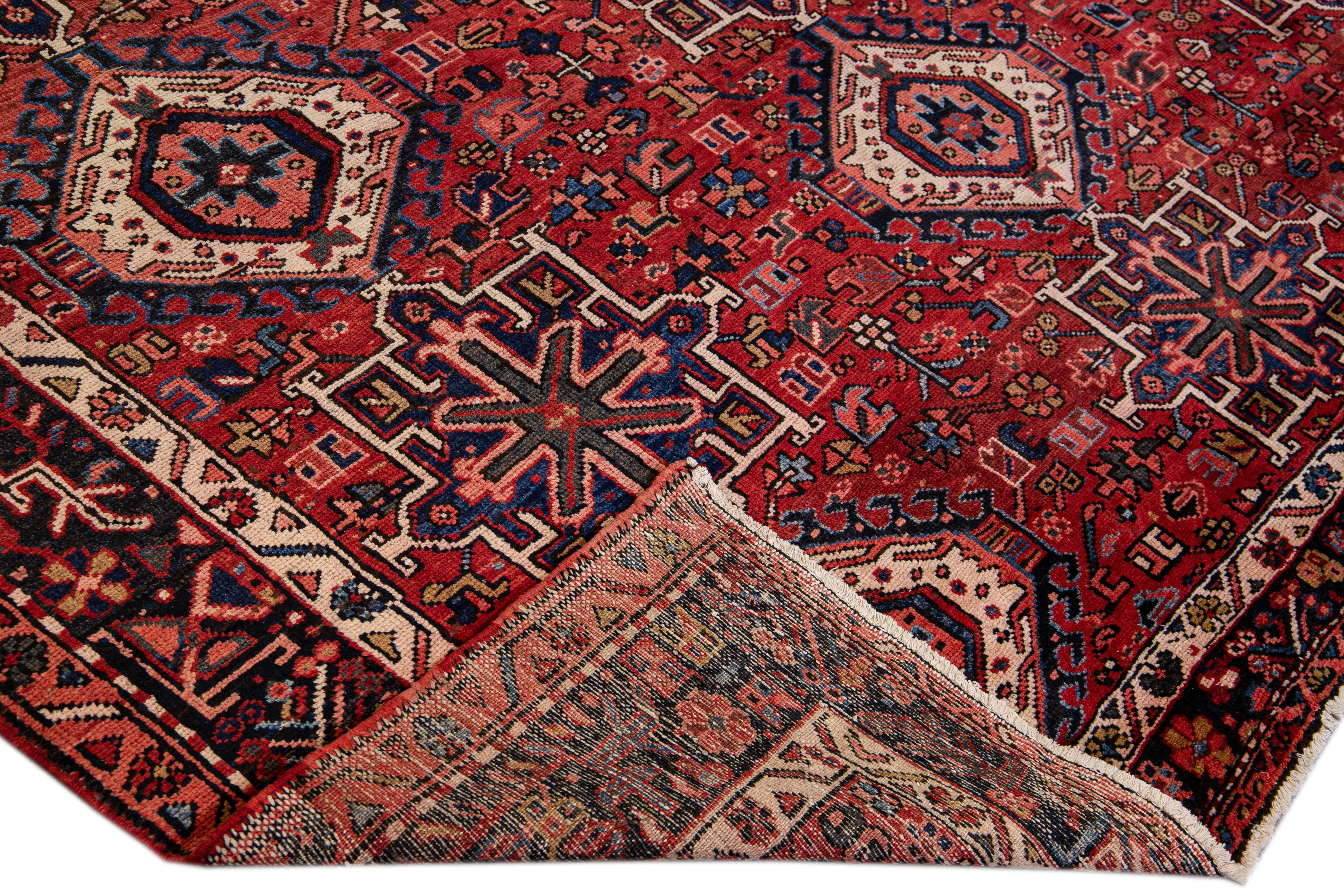 Beautiful antique Heriz hand-knotted wool rug with a red field. This Persian rug has a blue-designed frame and multicolor accents in an all-over gorgeous geometric medallion floral motif.

This rug measures: 8'10