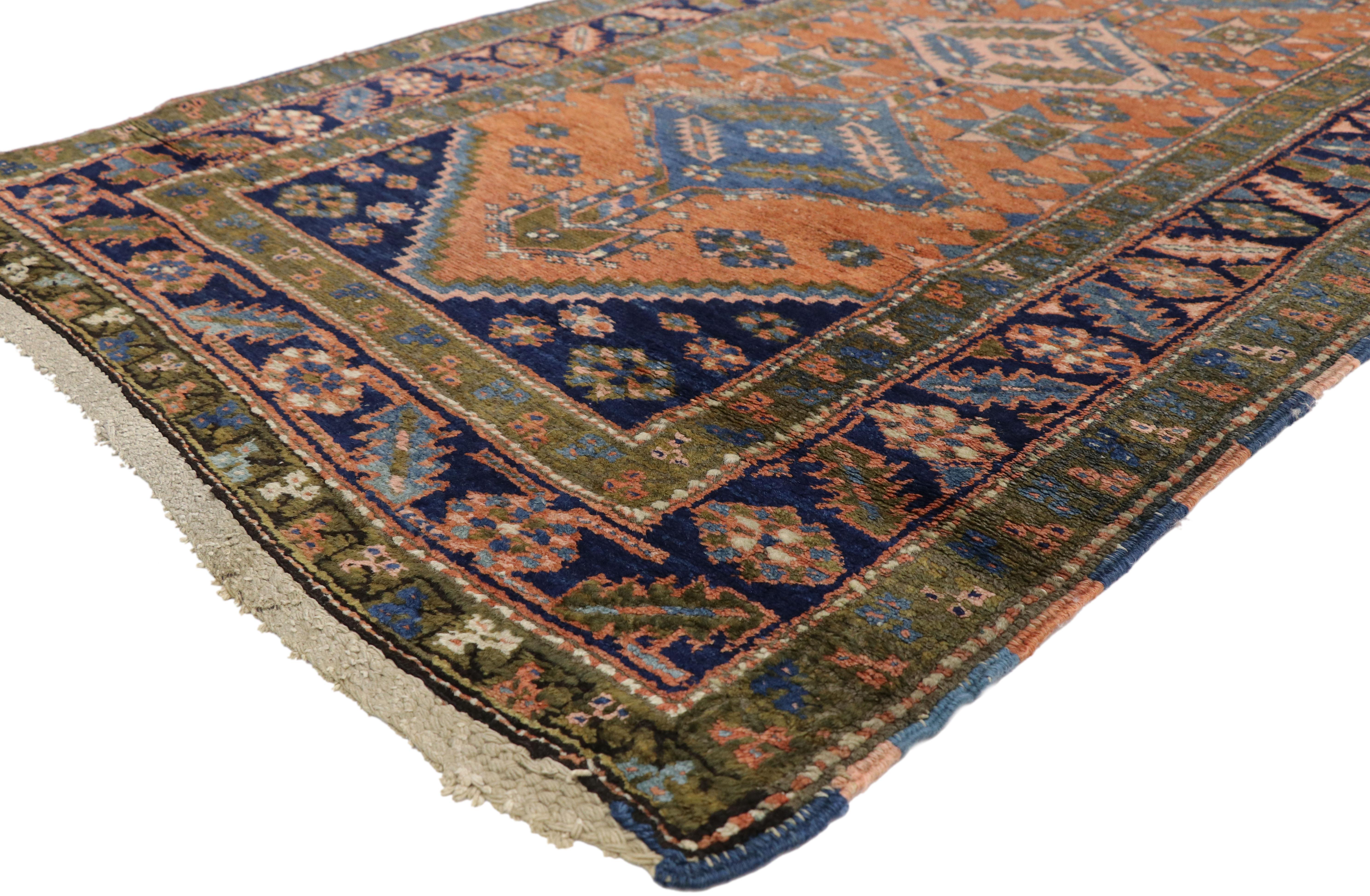Antique hand-knotted wool Persian Heriz runner featuring alternating medallions with an all-over geometric design on an orange field. Surrounded by a blue border with serrated tribal motifs. Highlighting rectilinear architectural elements and Art