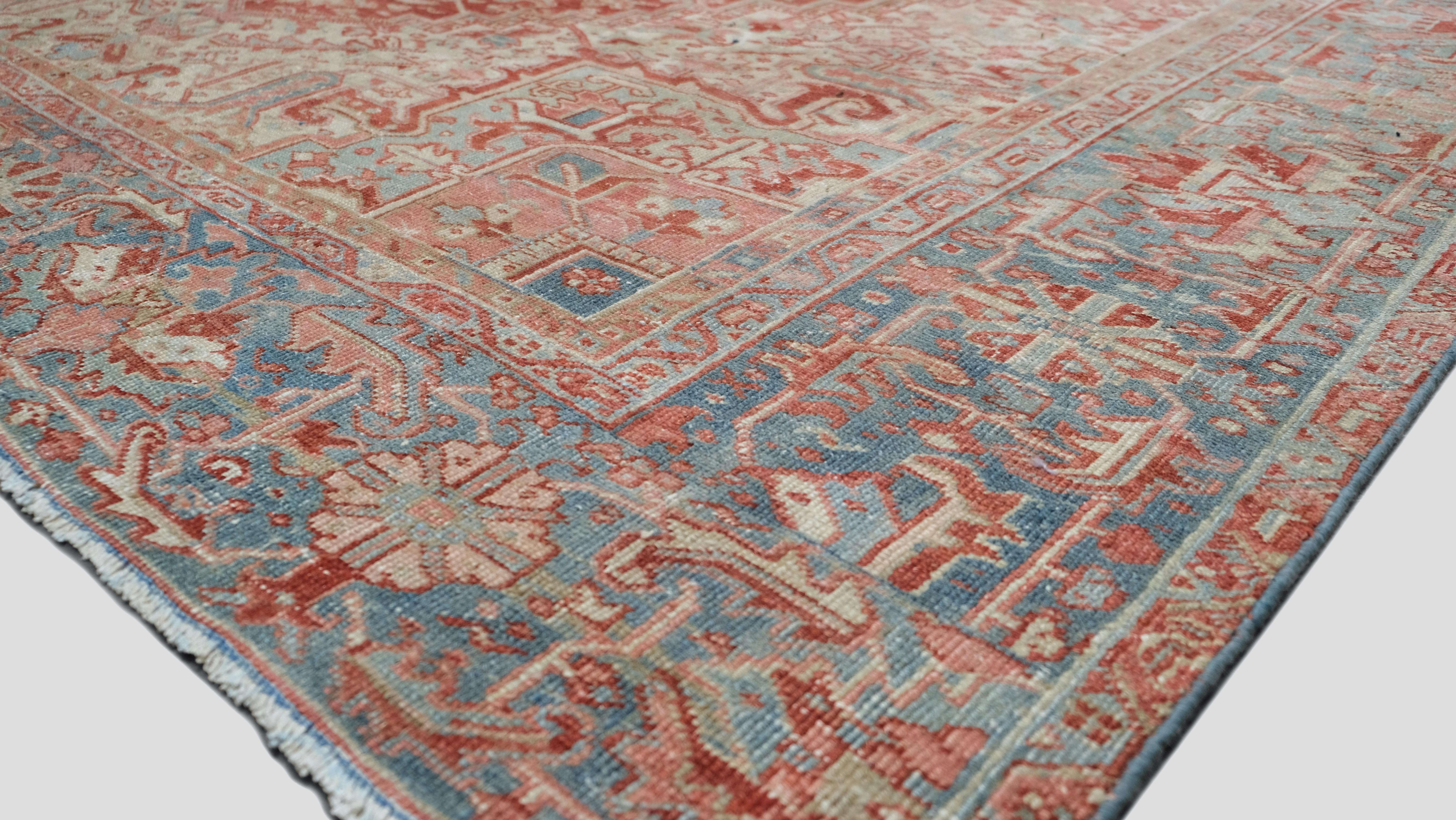 Cet exquis tapis ancien en laine nouée à la main de Heriz arbore un motif géométrique audacieux, harmonieusement encadré par des motifs tribaux complexes et une bordure finement détaillée. Sa riche palette de rouges et de bleus doux crée une