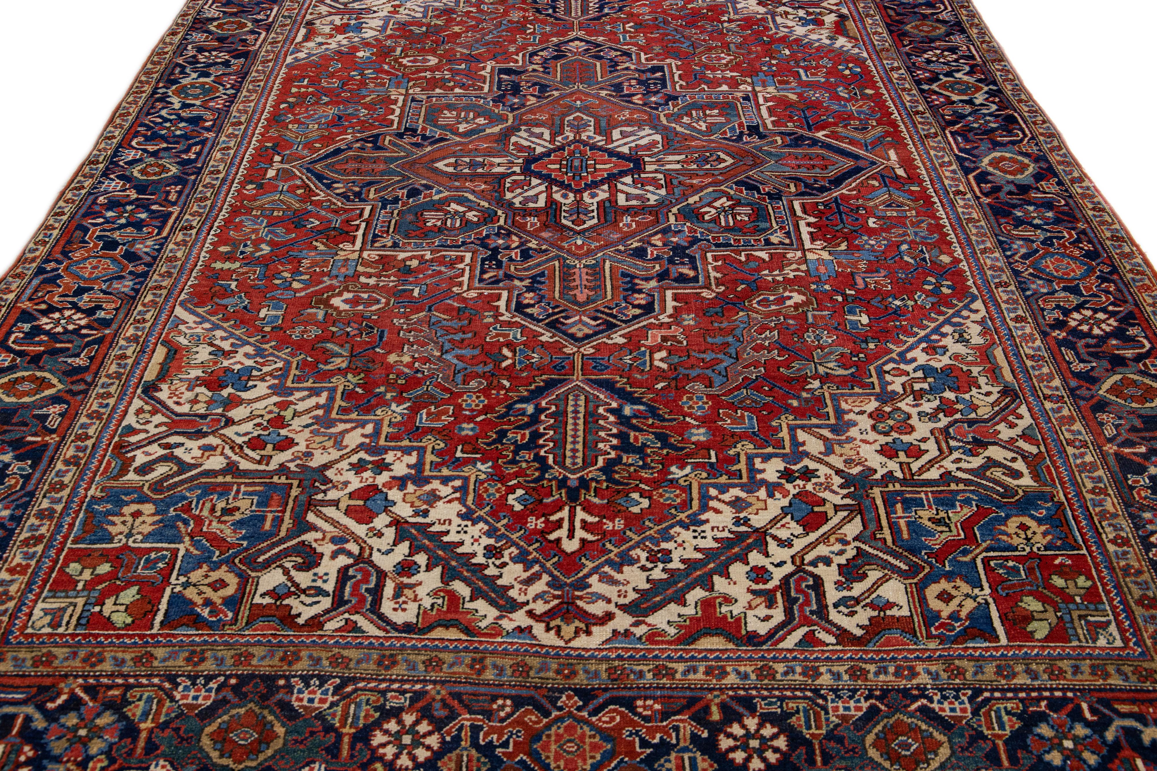 Beautiful antique Heriz hand-knotted wool rug with a red color field. This Persian rug has multicolor accents in a gorgeous all-over medallion floral motif.

This rug measures: 8'2