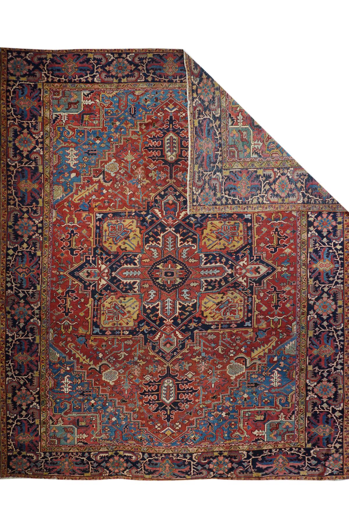 Antique Heriz rug 12' x 14'7''. Iconic NW Persian rustic carpet with a stepped and pointed madder field, light/medium blue corners, and a central eight radiating palmette navy octogramme. Red sub-medallion and navy ragged palmette pendants. Navy