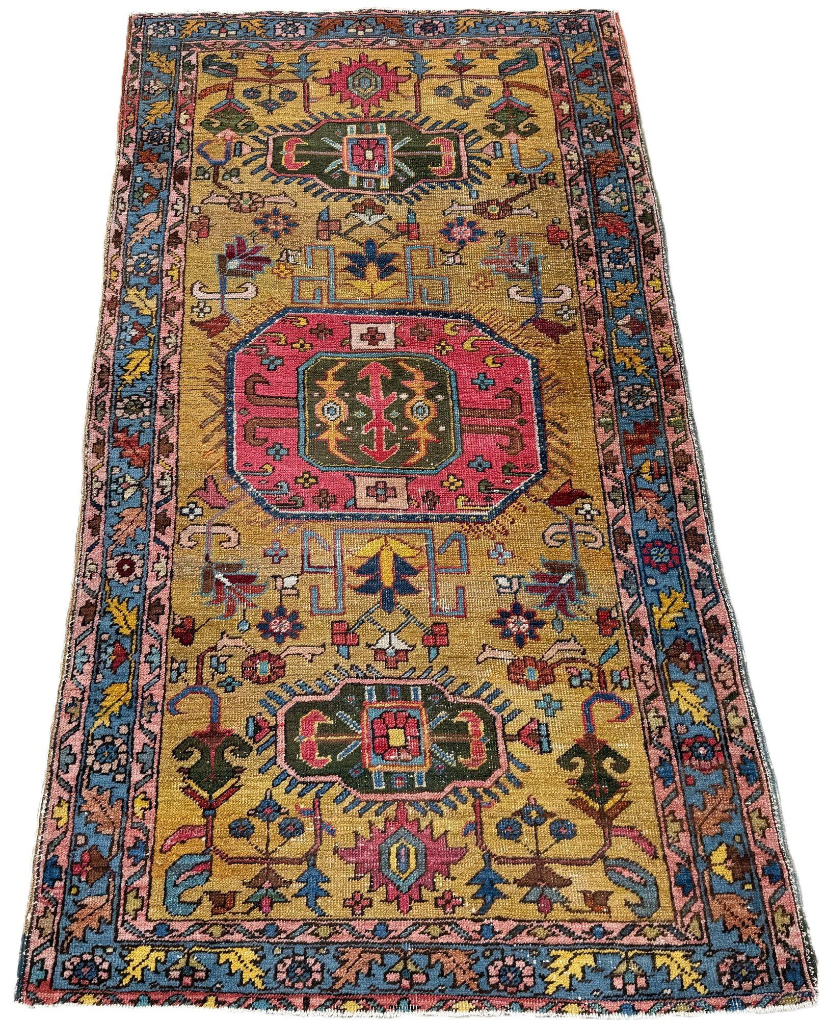 Ein seltener antiker Heriz-Teppich, handgewebt um 1900, möglicherweise etwas früher. Das Design zeigt ein geometrisches, rosafarbenes Medaillon, das eher an kaukasische Teppiche erinnert, auf einem ungewöhnlichen goldenen Feld, das von einer weichen