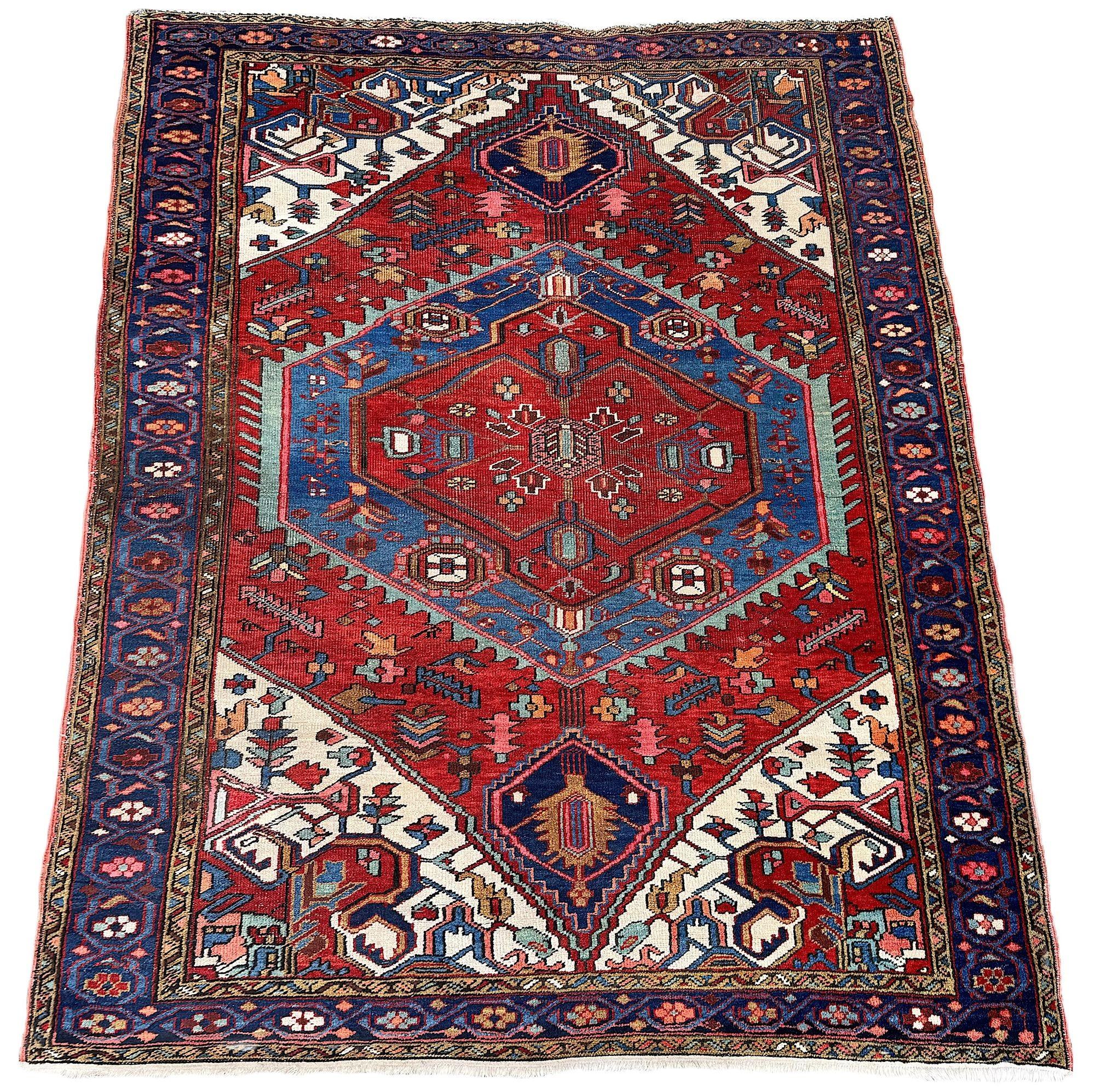 A lovely antique Heriz rug, woven circa 1910. The design features a large geometrical medallion on a rich terracotta field surrounded by a classic deep indigo border. Very attractive secondary colours of greens, pinks and golds and particularly the