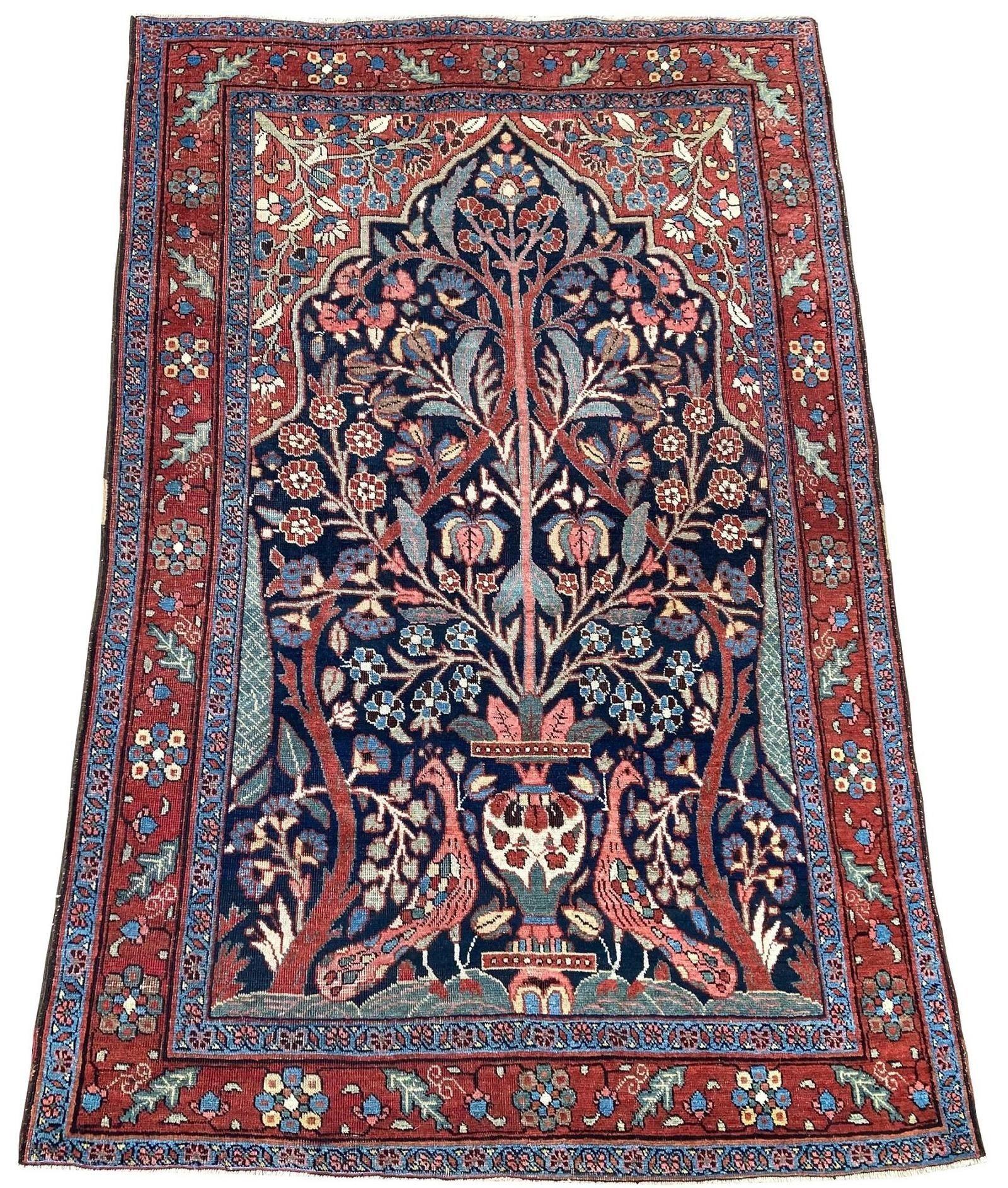 Un fabuleux tapis Heriz ancien, tissé à la main vers 1900, avec un motif inhabituel de vase flanqué de deux paons (à l'air légèrement désintéressé !) sur un champ indigo foncé et de superbes couleurs secondaires. Inhabituel de par sa conception et