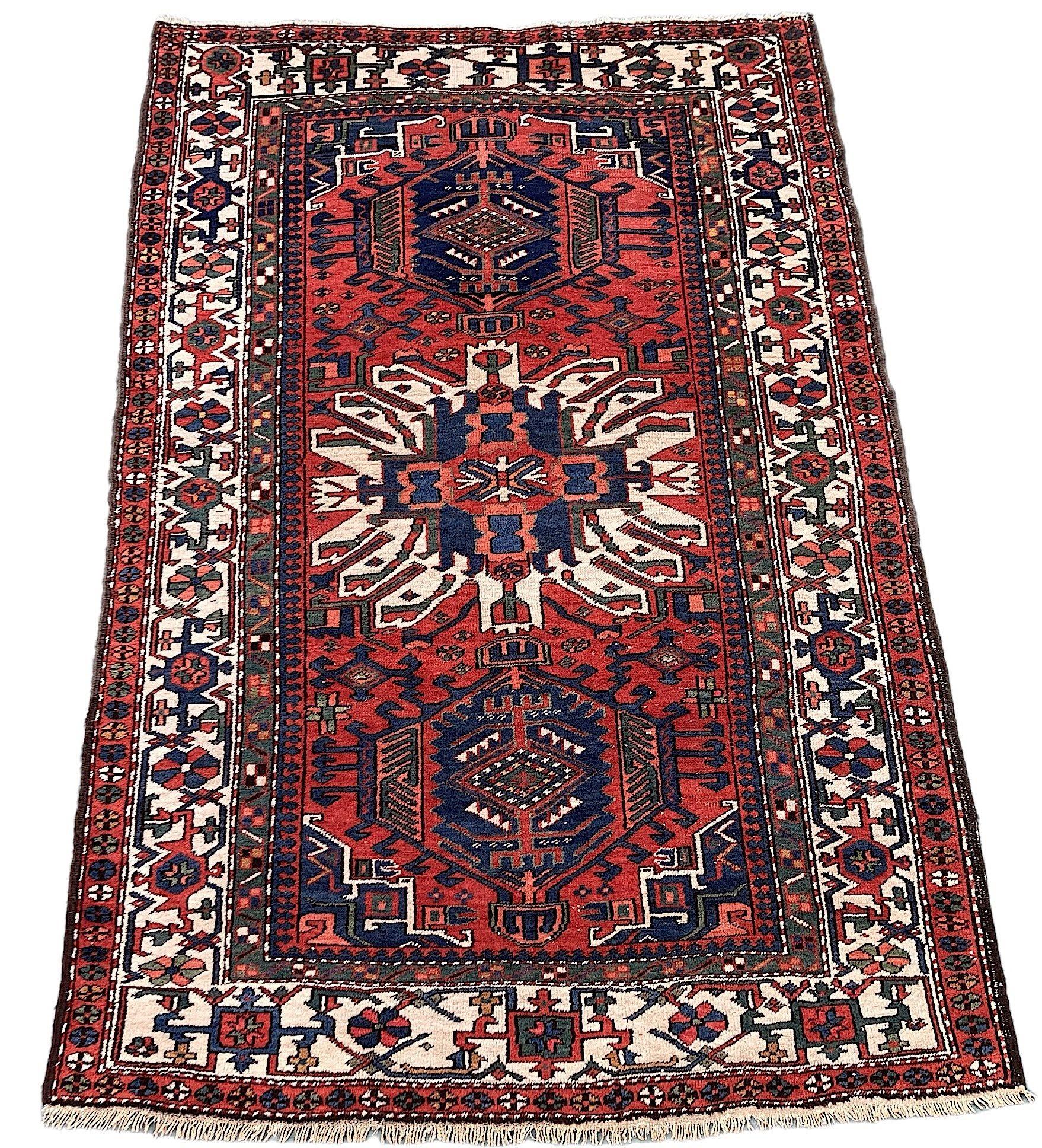 A beautiful antique Heriz rug, hand woven circa 1910. The design features 3 geometrical medallions on a rich red field surrounded by a wide, ivory border. Particularly attractive secondary colours of greens, golds and pinks.
Size: 2.05m x 1.37m (6ft