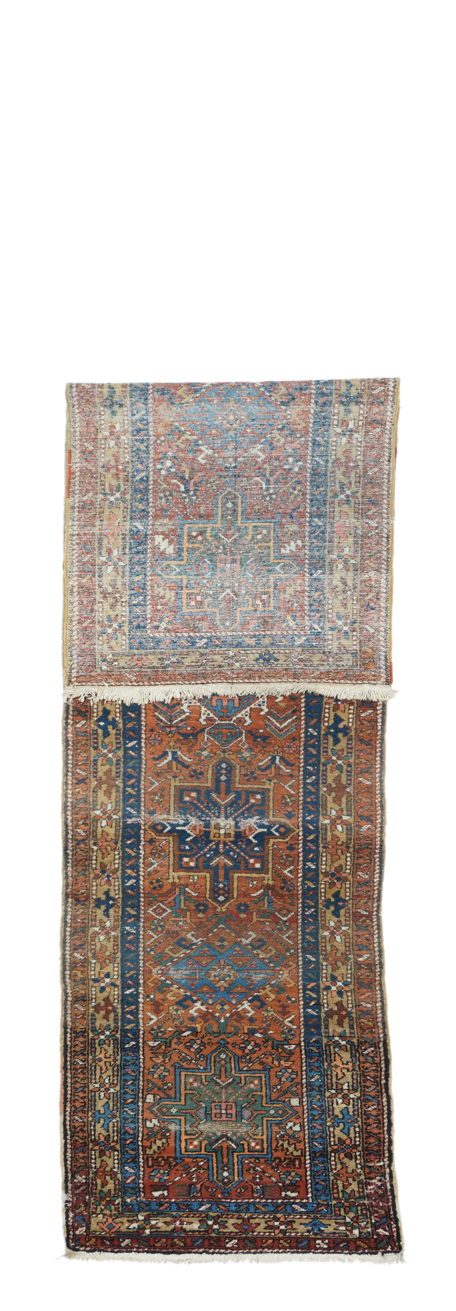 This NW Persian rustic runner from the Greater Heriz Weaving District, shows several horizontal lines of stair wear on a tomato red field decorated with seven medallions: hooked lozenges, ecru-hooked hexagons, and blue or green octogrammes. Stylised