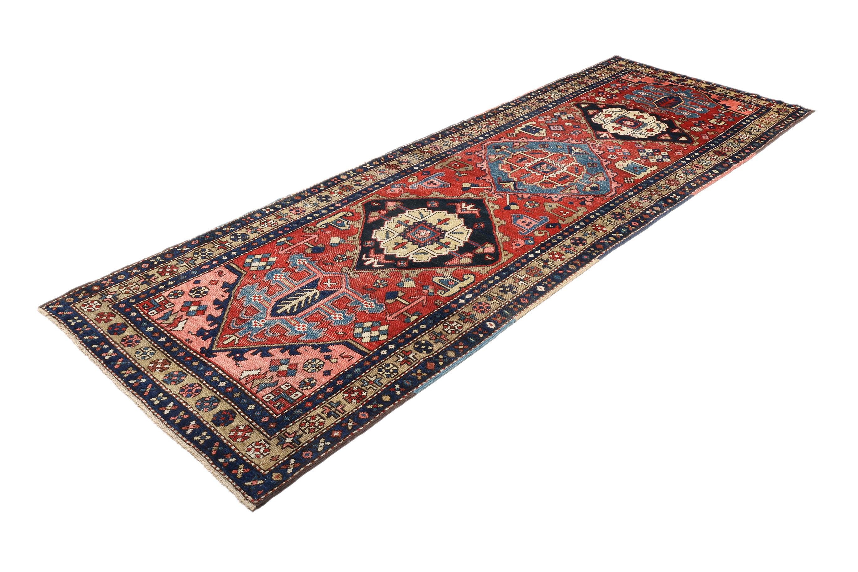 Authentique tapis persan Heriz, noué à la main en Iran, vers 1920.

Motif géométrique frappant en forme de médaillon avec des tons rouges audacieux et des accents indigo profonds.

Poil de laine durable sur une base de coton, assurant à la fois