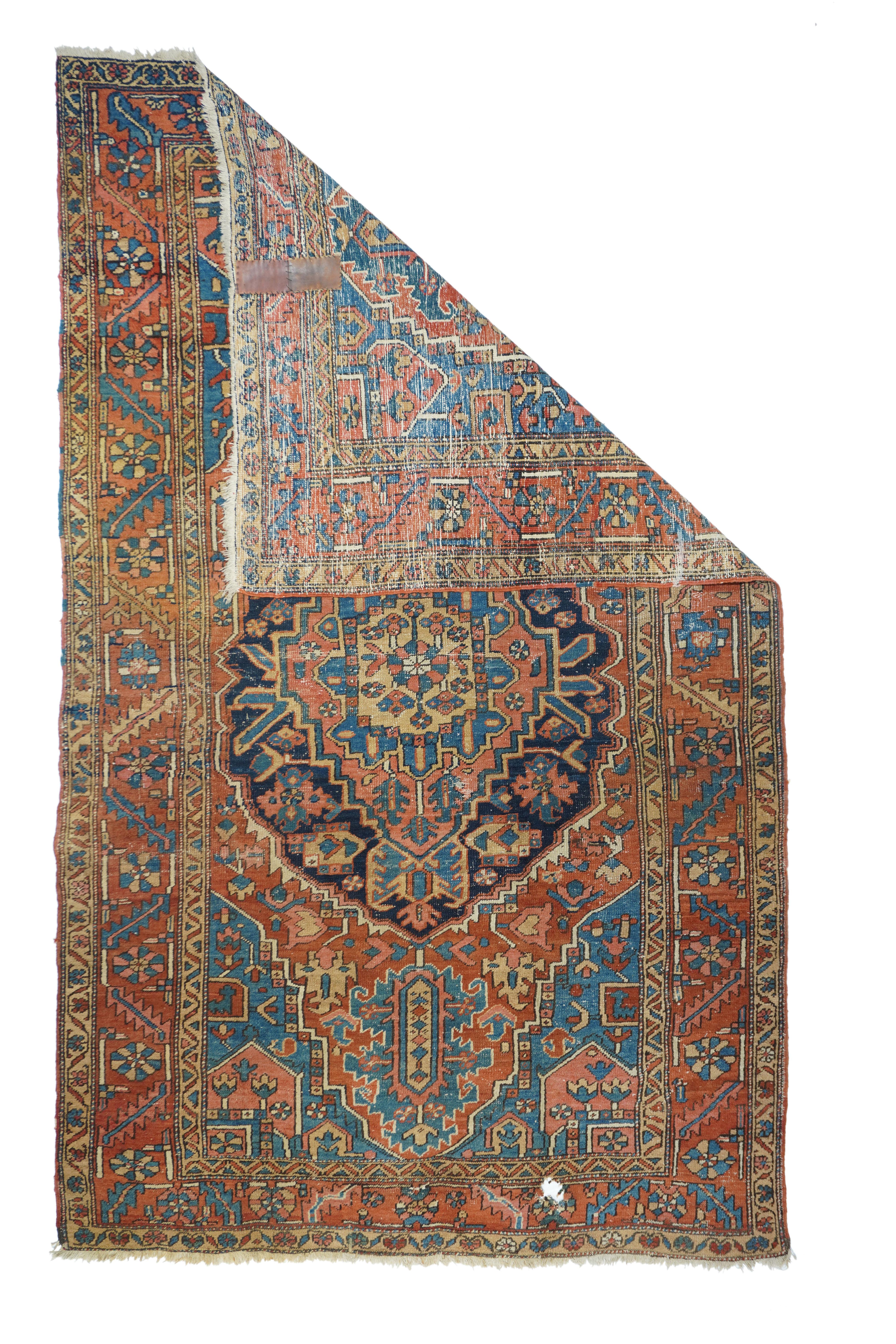 Antique Heriz rug 6'1'' x 10'2''. The jaunty, irregular oval navy medallion encloses a rose and yellow layered sub-medallion. Giant medium blue ragged palmette pendants. Light blue and rose corners. Rust red border with rosettes and slanted serrated
