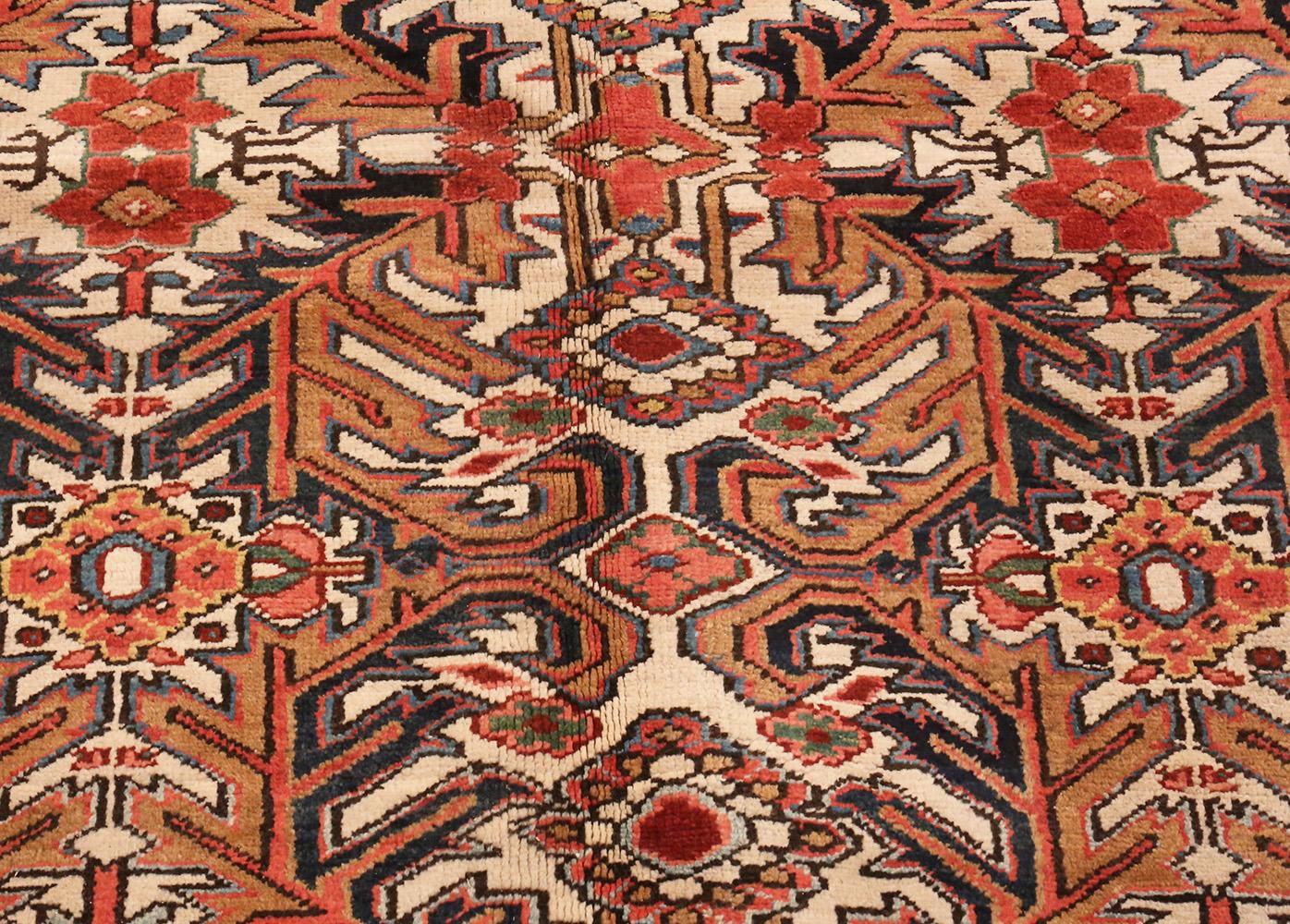 This awe-inspiring antique Persian Heriz carpet displays a host of powerful angular decorations arranged in a sophisticated all-over repeating pattern that retains a rustic village-like appearance. The same angular features that give regional