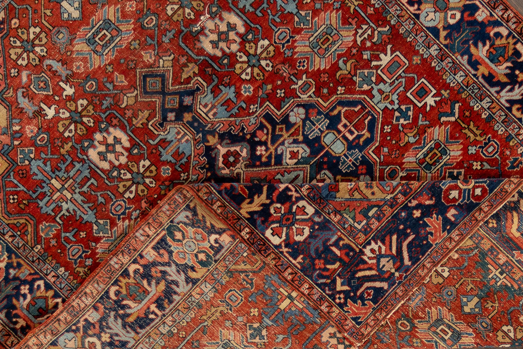 A 20th century vintage Heriz rug with a red field, border and a center medallion motif. This rug measures at 7'4