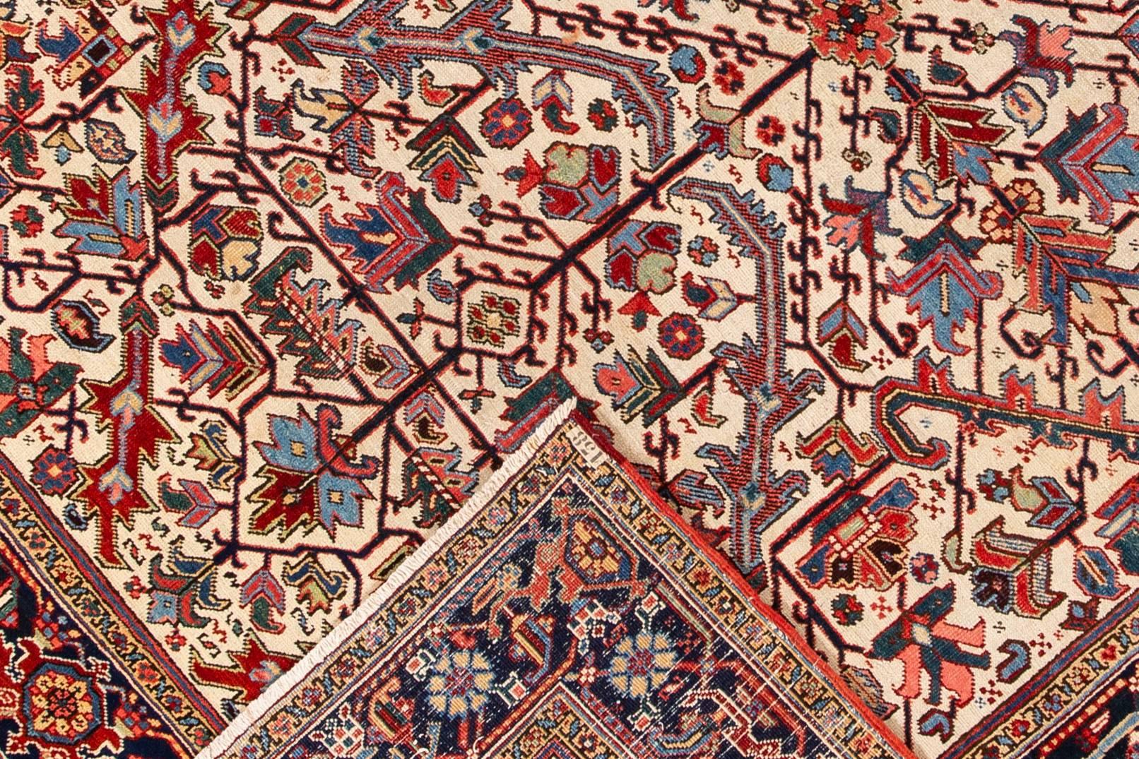 A hand-knotted antique Heriz rug with an allover geometric design on a ivory field. This rug measures 7'0