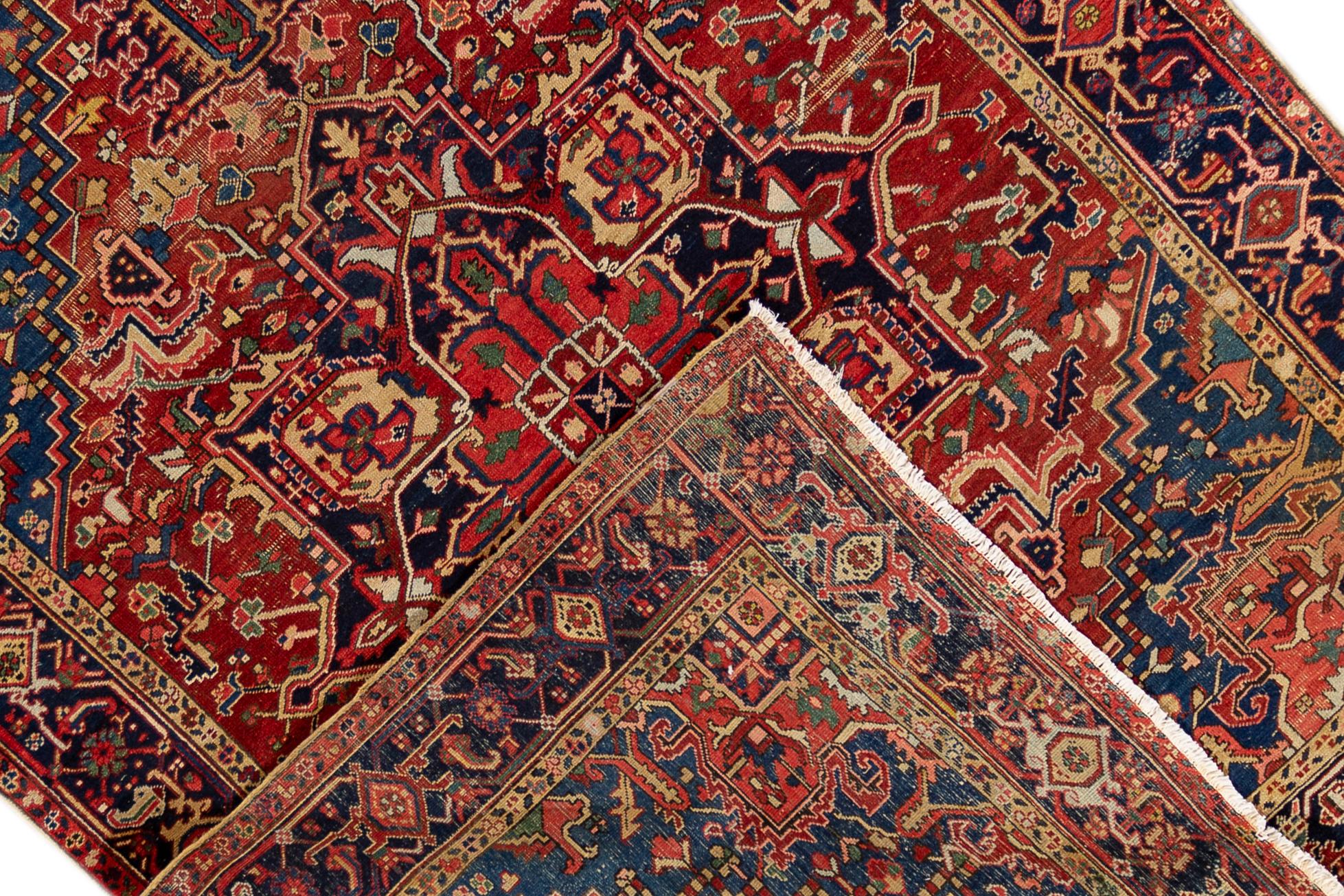 An early 20th century antique Heriz rug with a centre medallion in an all over geometric red and blue motif and a border. This rug measures at 7'9