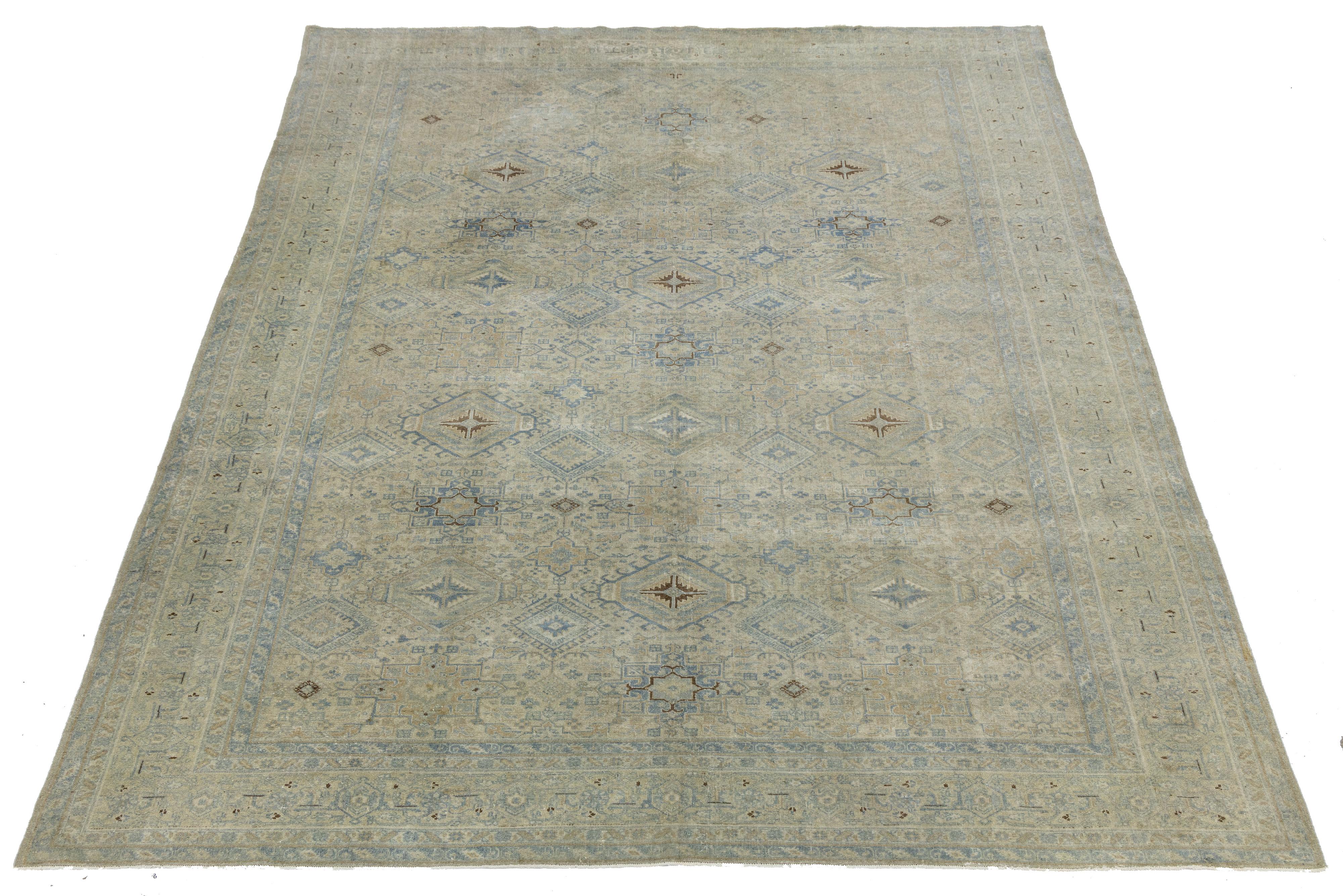 Questo tappeto Heriz autentico e antico presenta una raffinata disposizione geometrica con motivi a stella e a diamante in tonalità tenui di beige, blu e marrone. Tessuto a mano in lana resistente, presenta un'abrasione naturale e un design