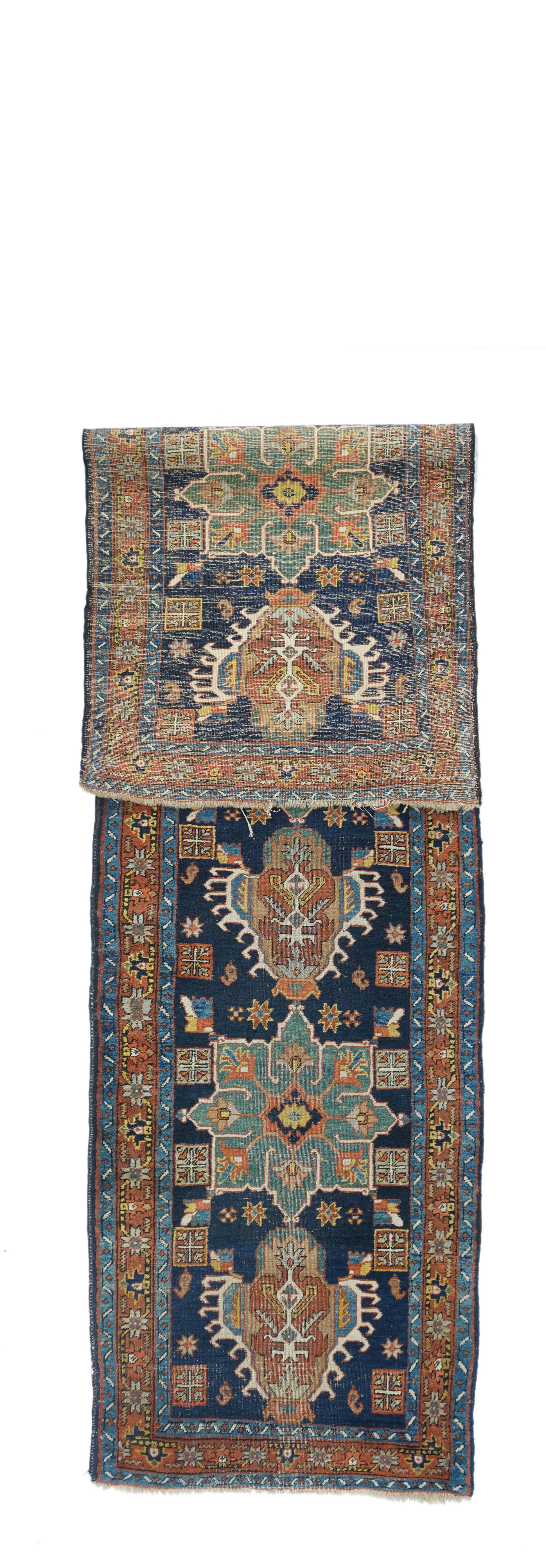 Antique Heriz runner 2'8'' x 10'8''. This classic NW Persian rustic Kenare (runner) shows the characteristic deep indigo ground decorated by seven alternating lea green octogrammes and red/ivory hooked 