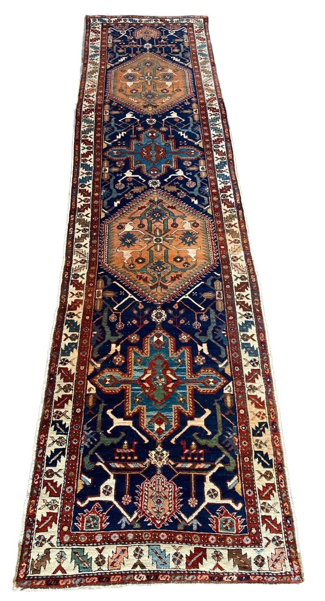 A lovely antique Heriz runner, handwoven circa 1900 with a geometrical design on a dark indigo field and ivory border. Full of rustic charm and great secondary colours. Note the interesting figures in the detail.
 
Size: 4.35m x 1.04m (14ft 3in x