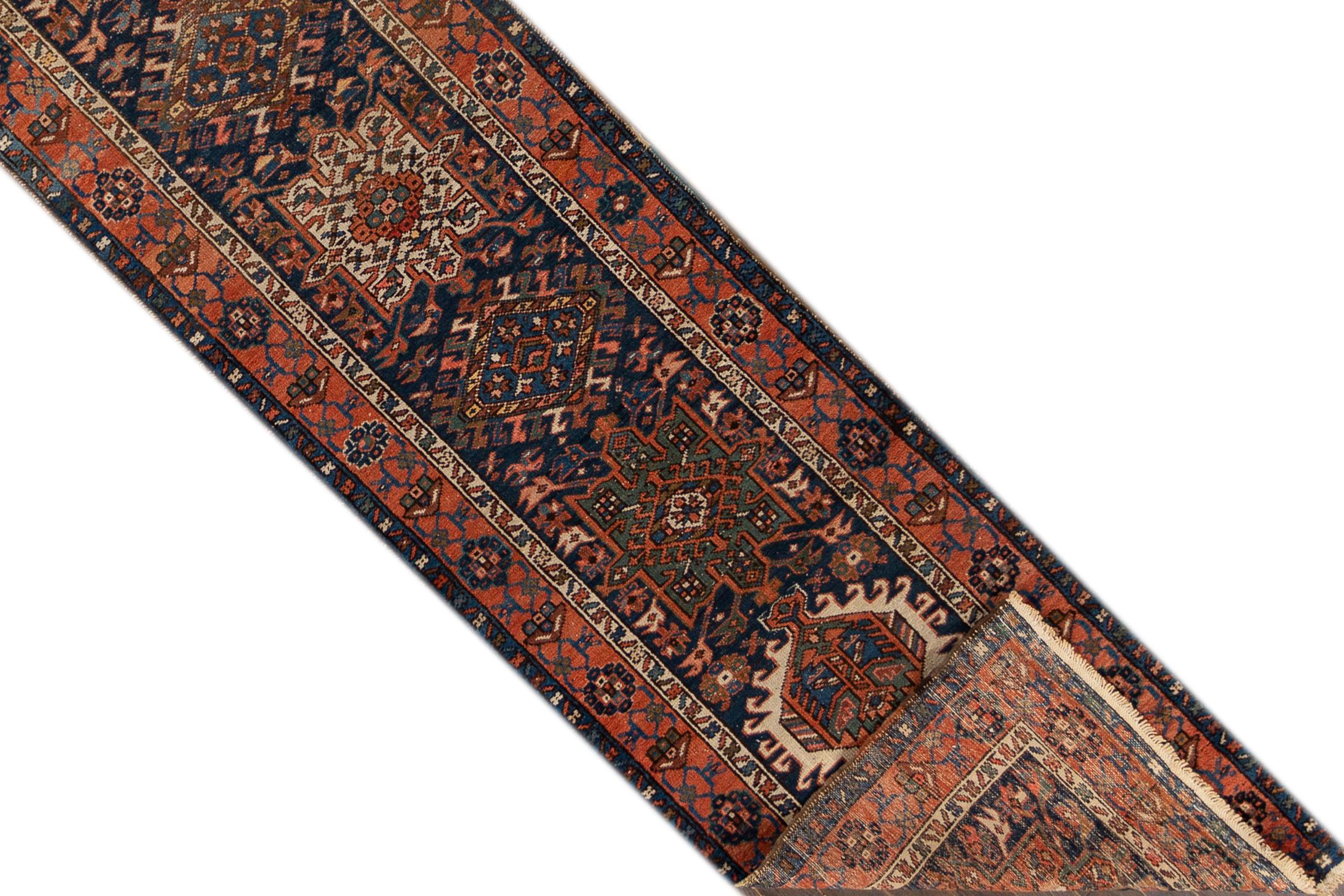 An early 20th century antique Heriz runner rug with a geometric multi medallion in an all over red and blue motif and a border. This rug measures at 2'10