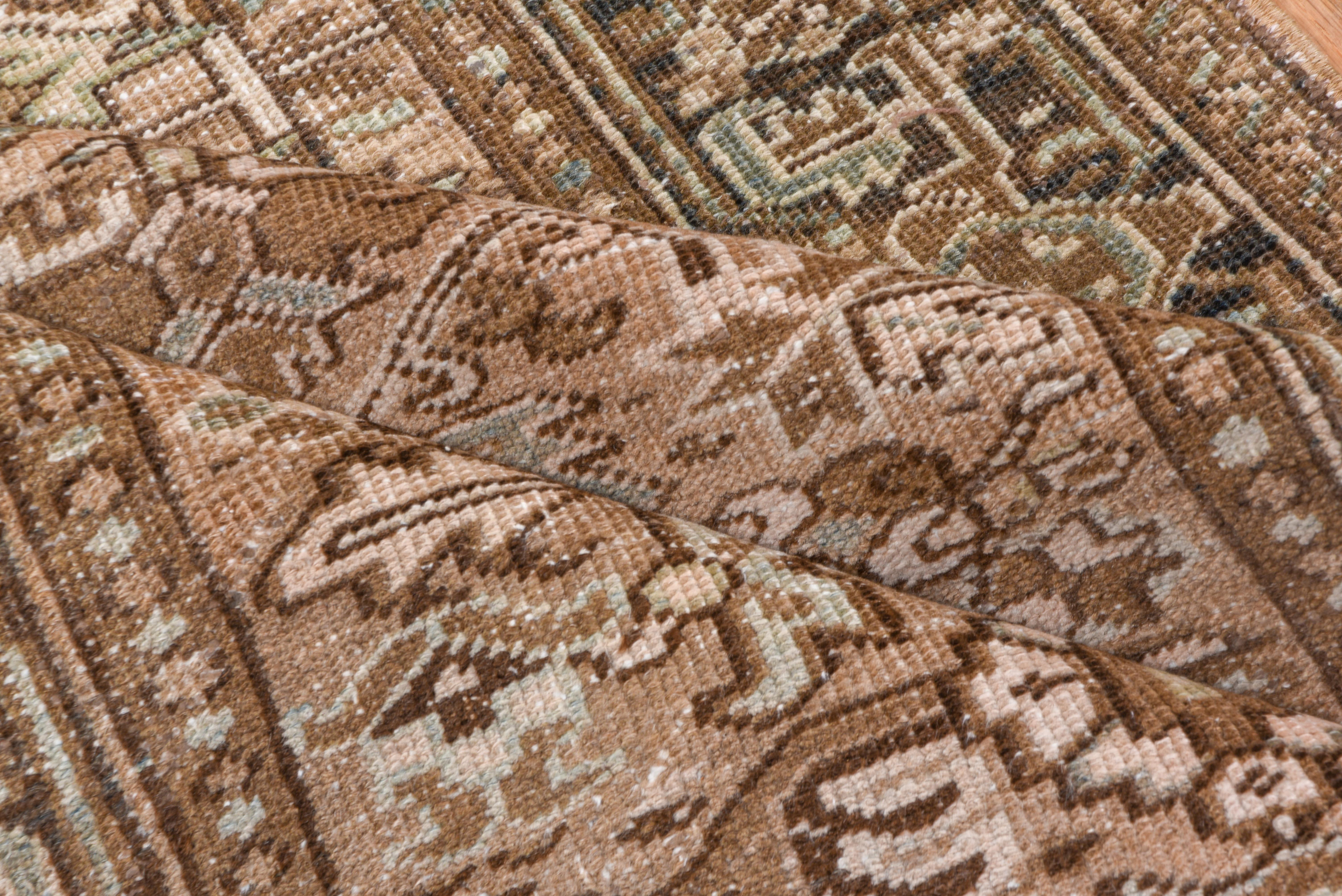 This antique Heriz runner features a vertical medallion layout woven in a grounded palette of taupe, sand, walnut, and pale blue. The central field displays stylized palmettes and angular vines framed by a multi-tiered border of geometric rosettes