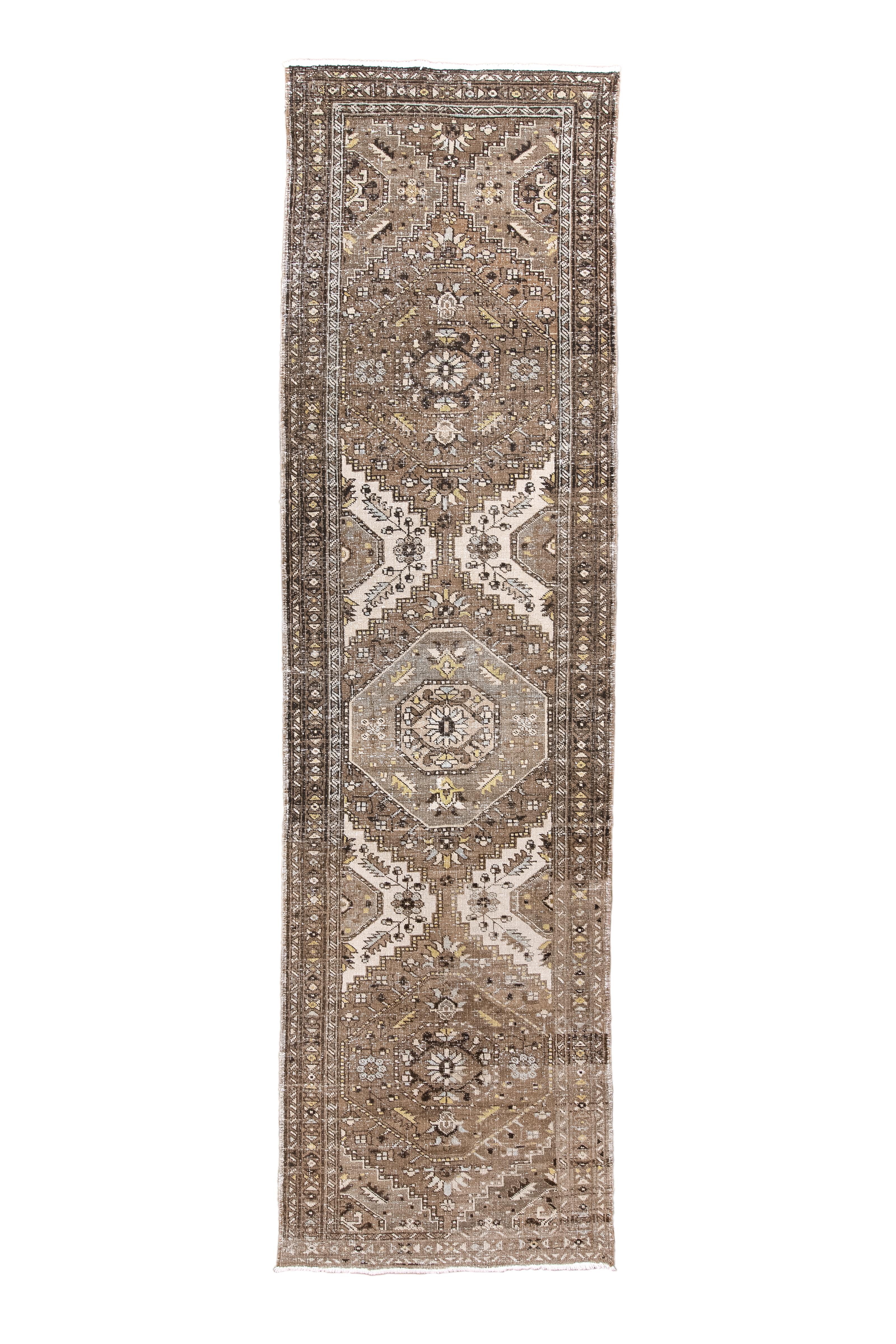 Le champ brun présente trois médaillons octogonaux. Quatre demi-médaillons écrus définissent le motif central.  Étroite bordure principale florale stylisée de X et de rosettes. Usure générale importante.

Taille du tapis
3'0x10'6