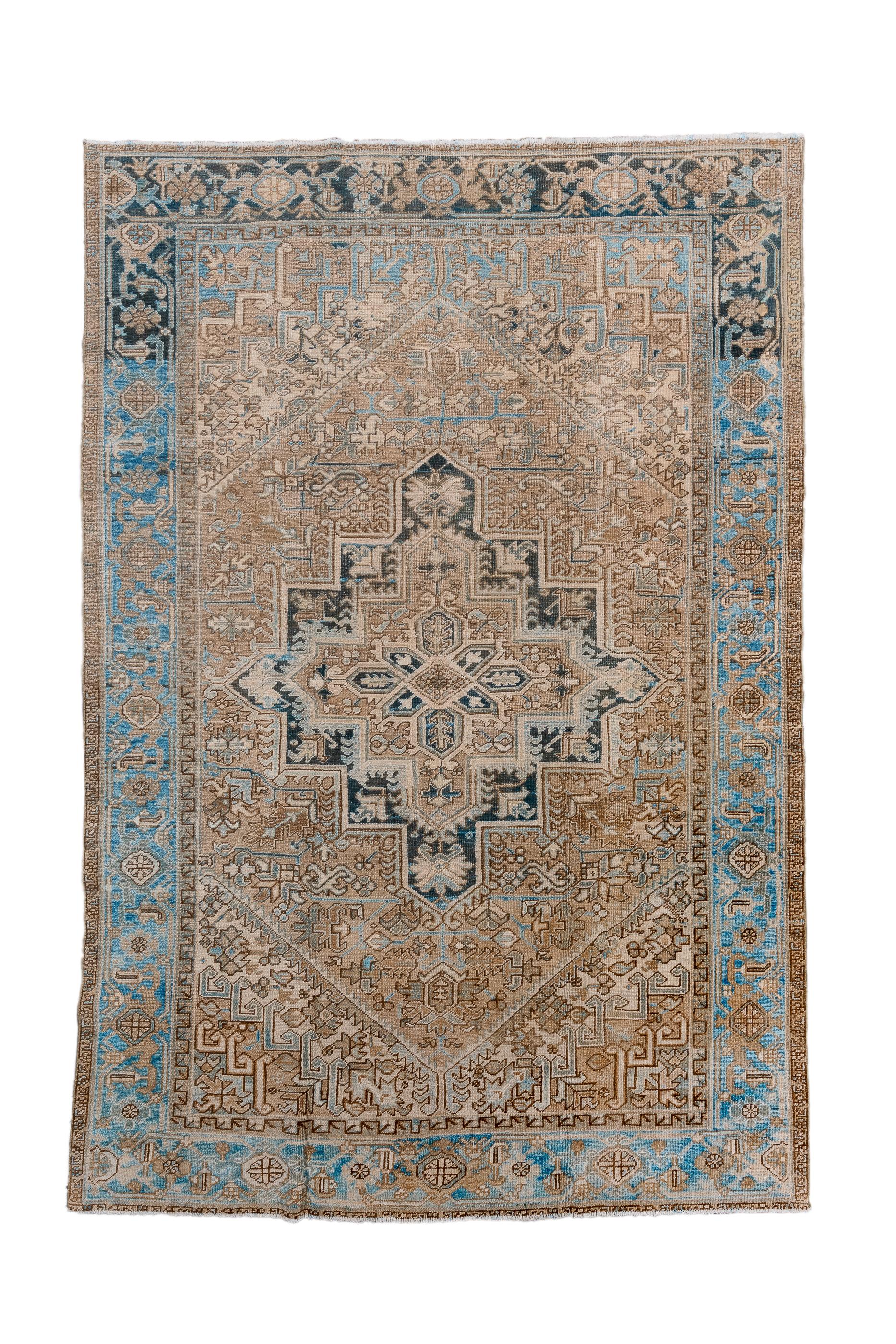 In the classic Heriz manner, but particularly geometric with simply and boldly stepped navy cartouche medallion, submedallion and octofoil central focus. Coral field. Triangular  cream corners with stepped sub-corners. Cerulean blue strip style main