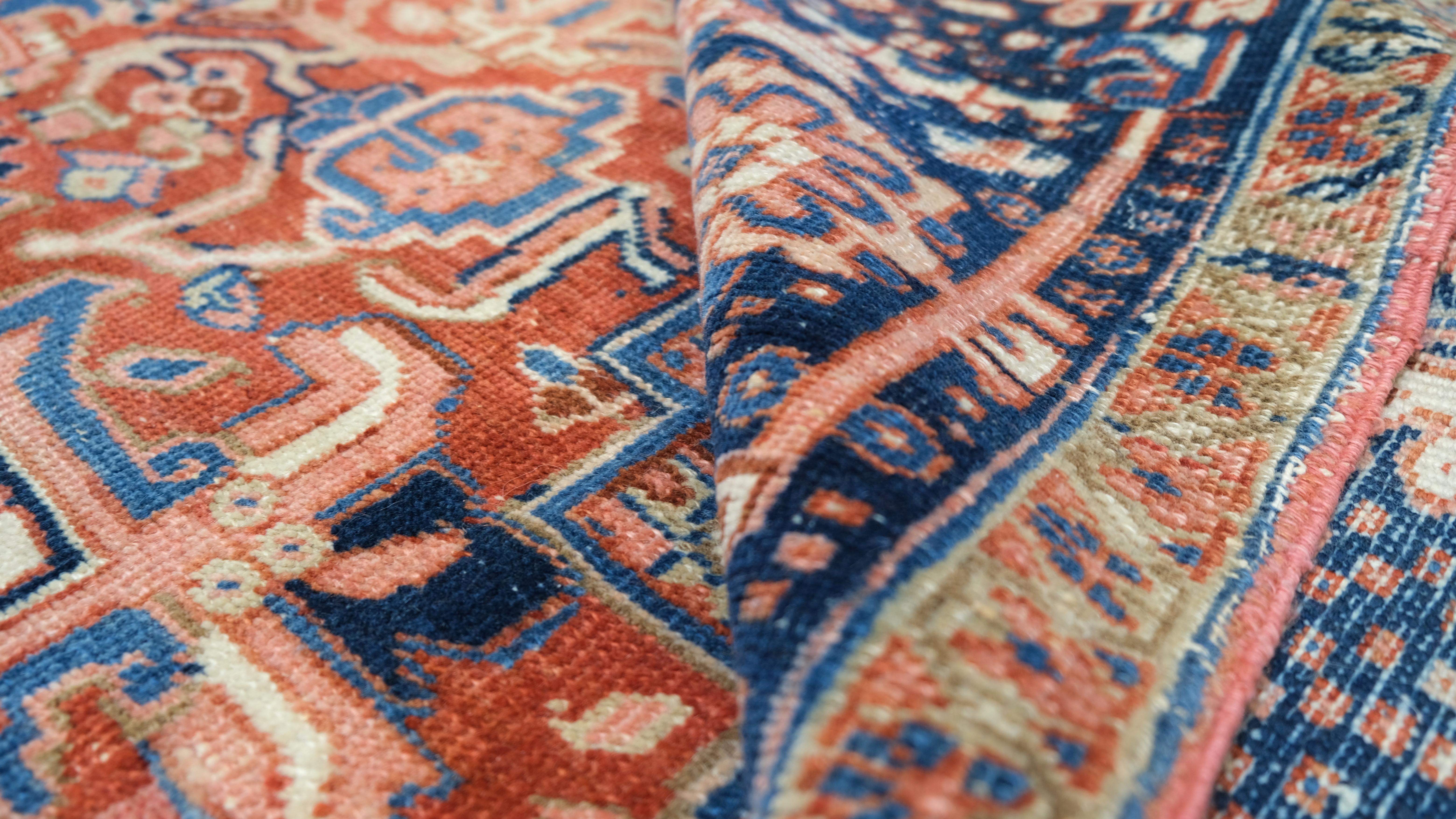 Un sorprendente medaglione geometrico Heriz al centro, circondato da intricati motivi tribali e motivi floreali angolari. La ricca palette di colori, con accenti di blu profondo, ruggine caldo e avorio, esalta il design audace e simmetrico del