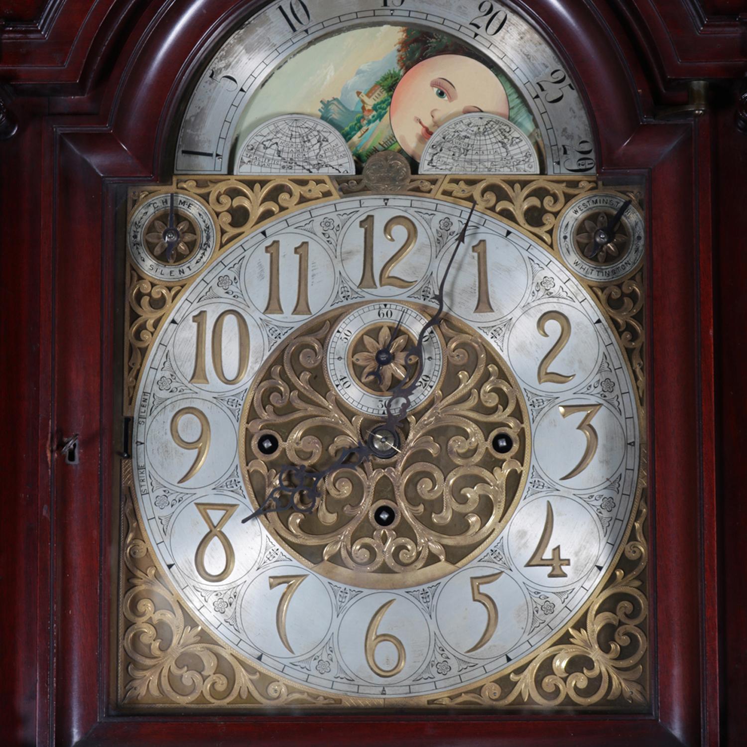 An antique long case clock by Herschede features carved mahogany case, reticulated moon phase face with Arabic numerals, works are German, without serial number (pre-dating 1911), and not working full time (possibly in need of cleaning), 9-tube and