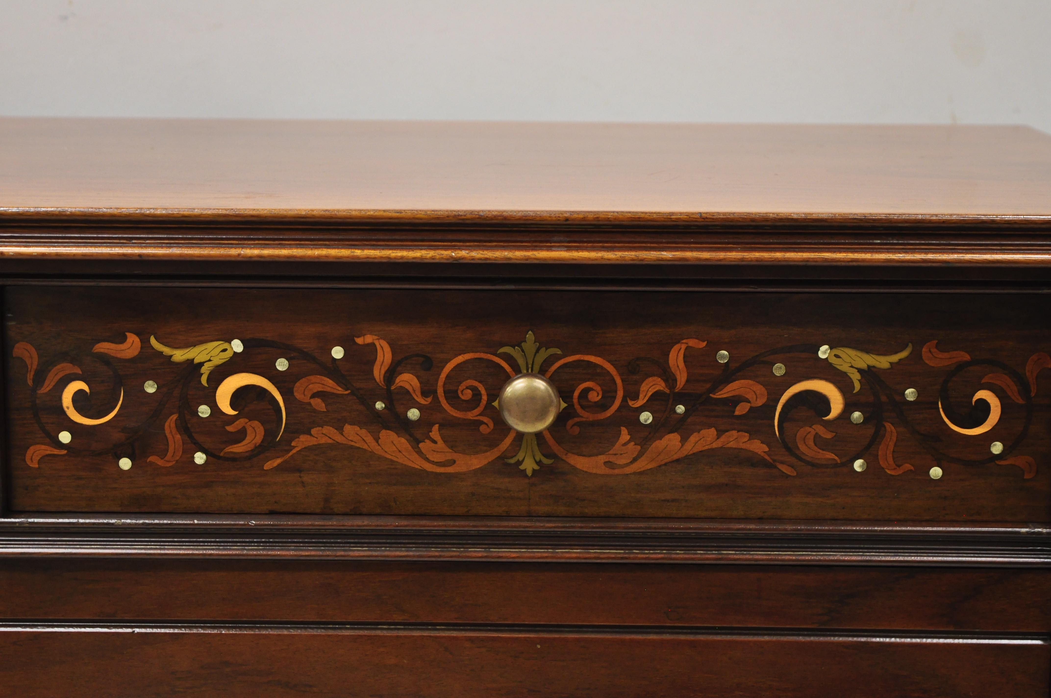 Antique Herts Brothers Edwardian bronze and satinwood inlay mahogany chest dresser. Item features brass and satinwood floral scrollwork inlay, brass/bronze capped feet, rolling casters, solid wood construction, beautiful wood grain, no key, but