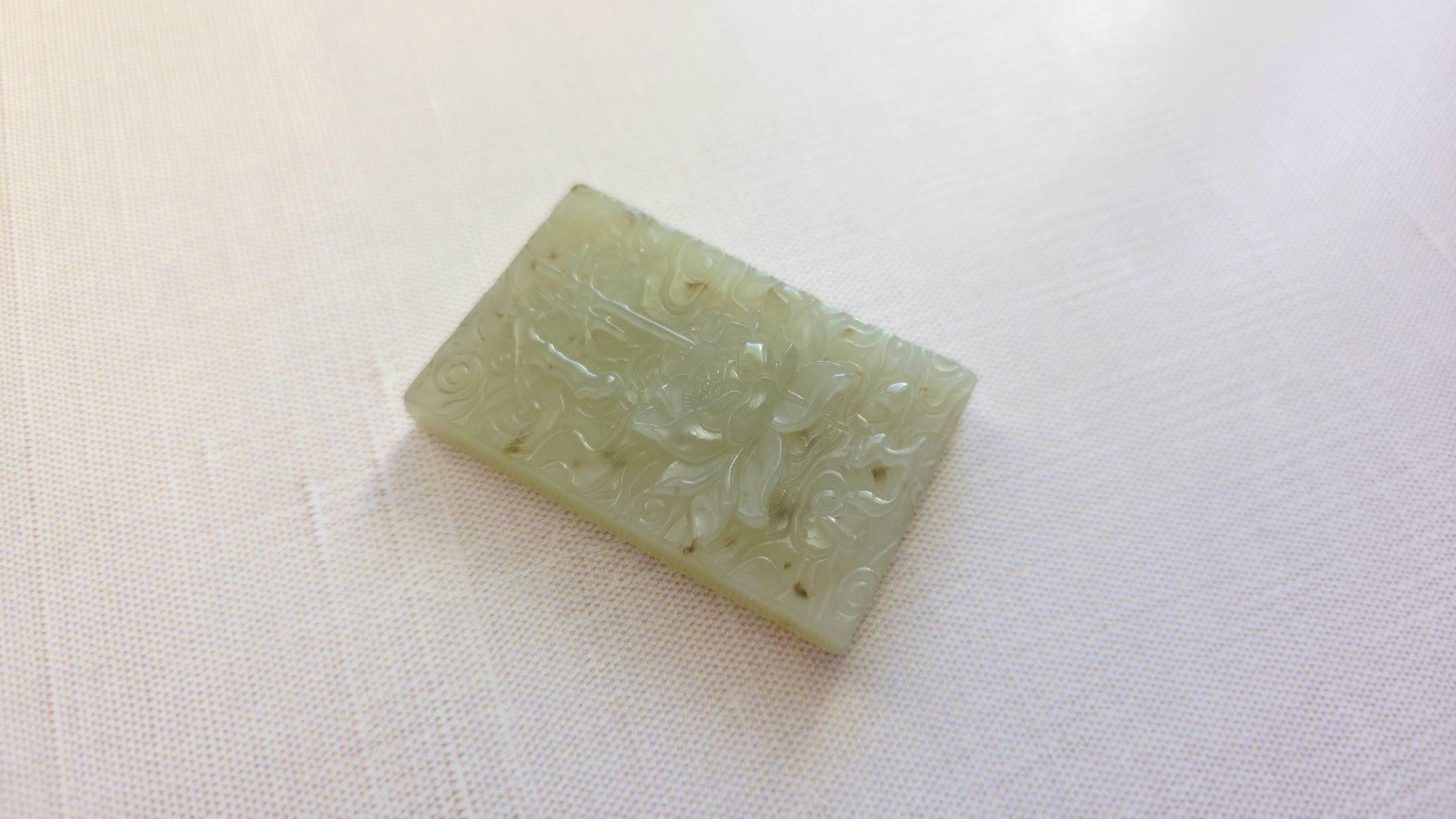 Siamo lieti di presentarti un antichissimo ciondolo-amuleto realizzato in giada Hetian, con una raffigurazione scolpita di un loto sull'acqua con geroglifici su un lato e un loto con geroglifici su ogni petalo del loto sull'acqua sull'altro lato.