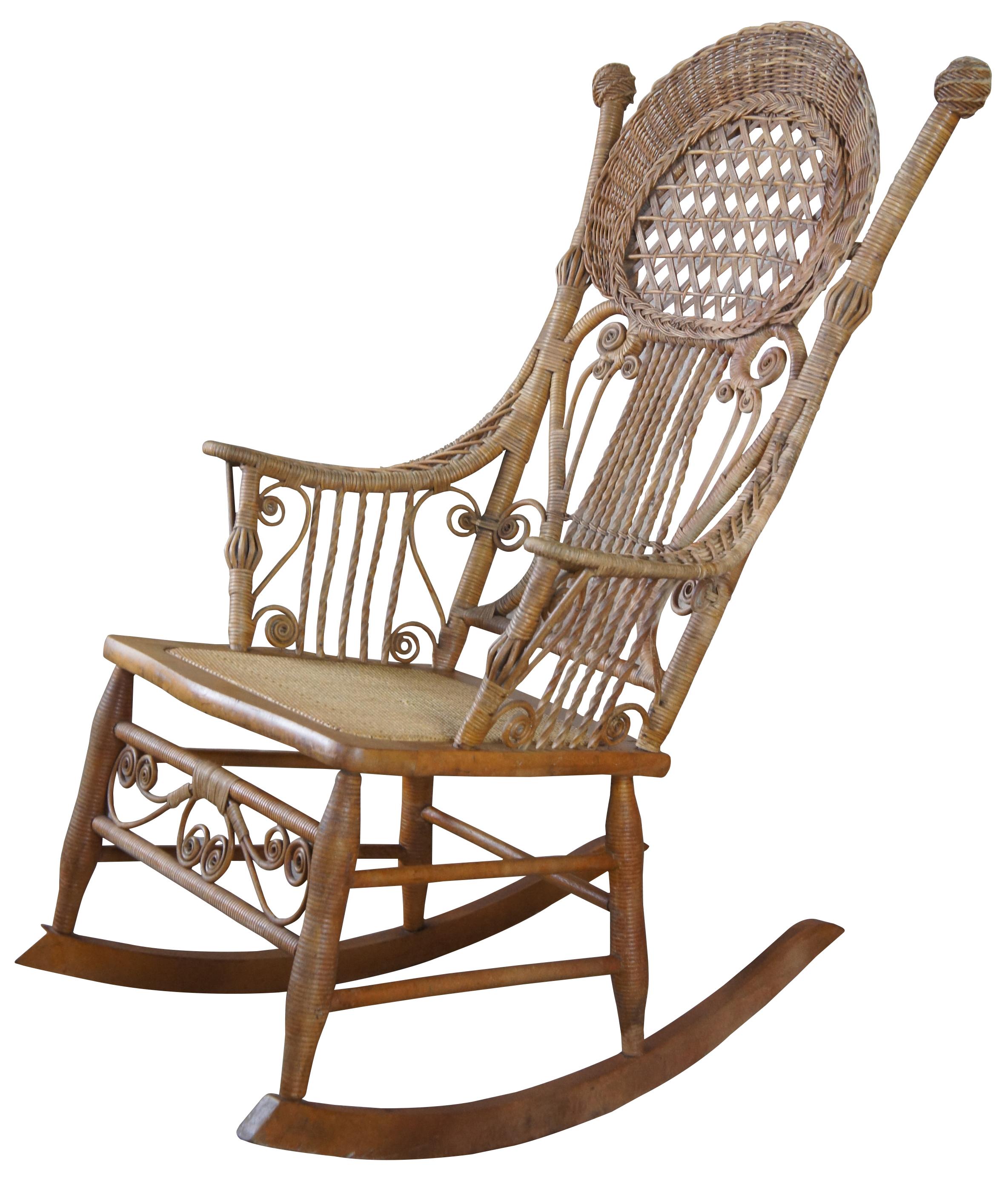 Early 1900s Heywood Wakefield Rocking chair. Features a wood frame wrapped in wicker with a rattan seat. Includes scrolled and twisted supports as well as braiding and lattice design. Remnants of original tag can be seen along the underside.
 