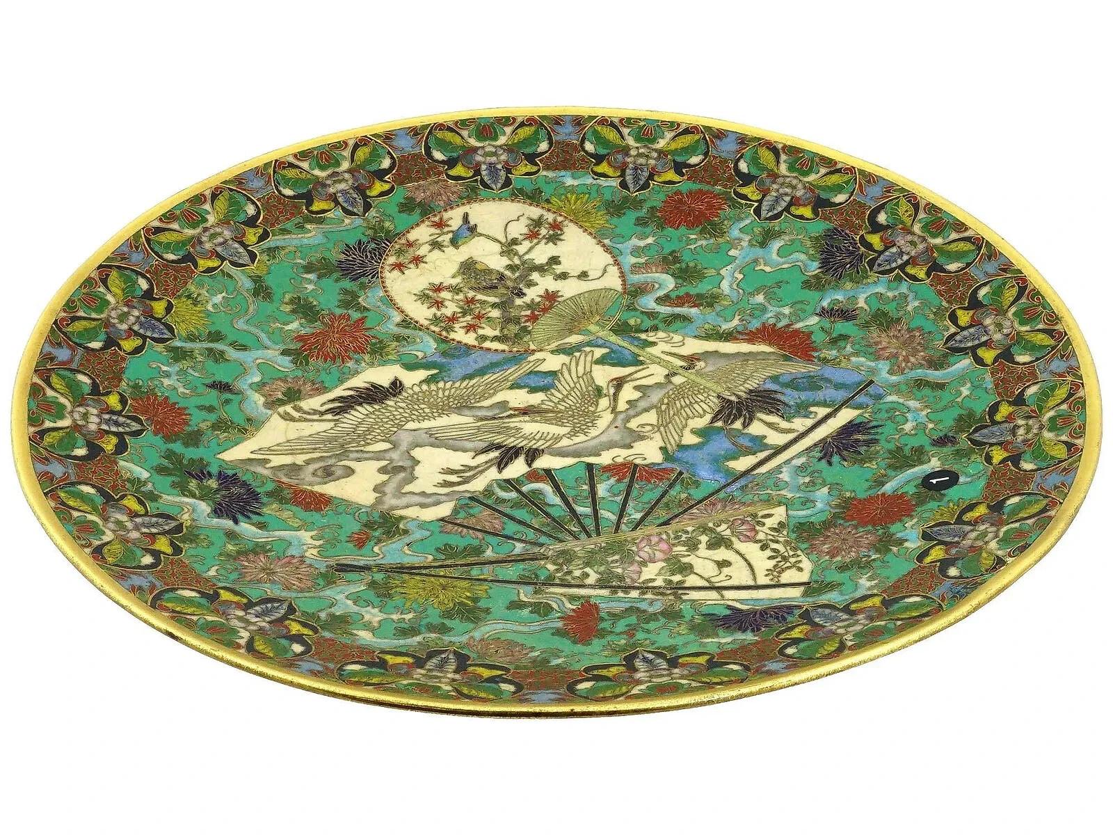 Un antico piatto da portata giapponese dell'epoca Meiji in ottone e smalto. Il piatto è superbamente smaltato con motivi policromi, tra cui tre ventagli raffiguranti fiori e uccelli, mentre lo sfondo è di un turchese brillante con lussureggianti