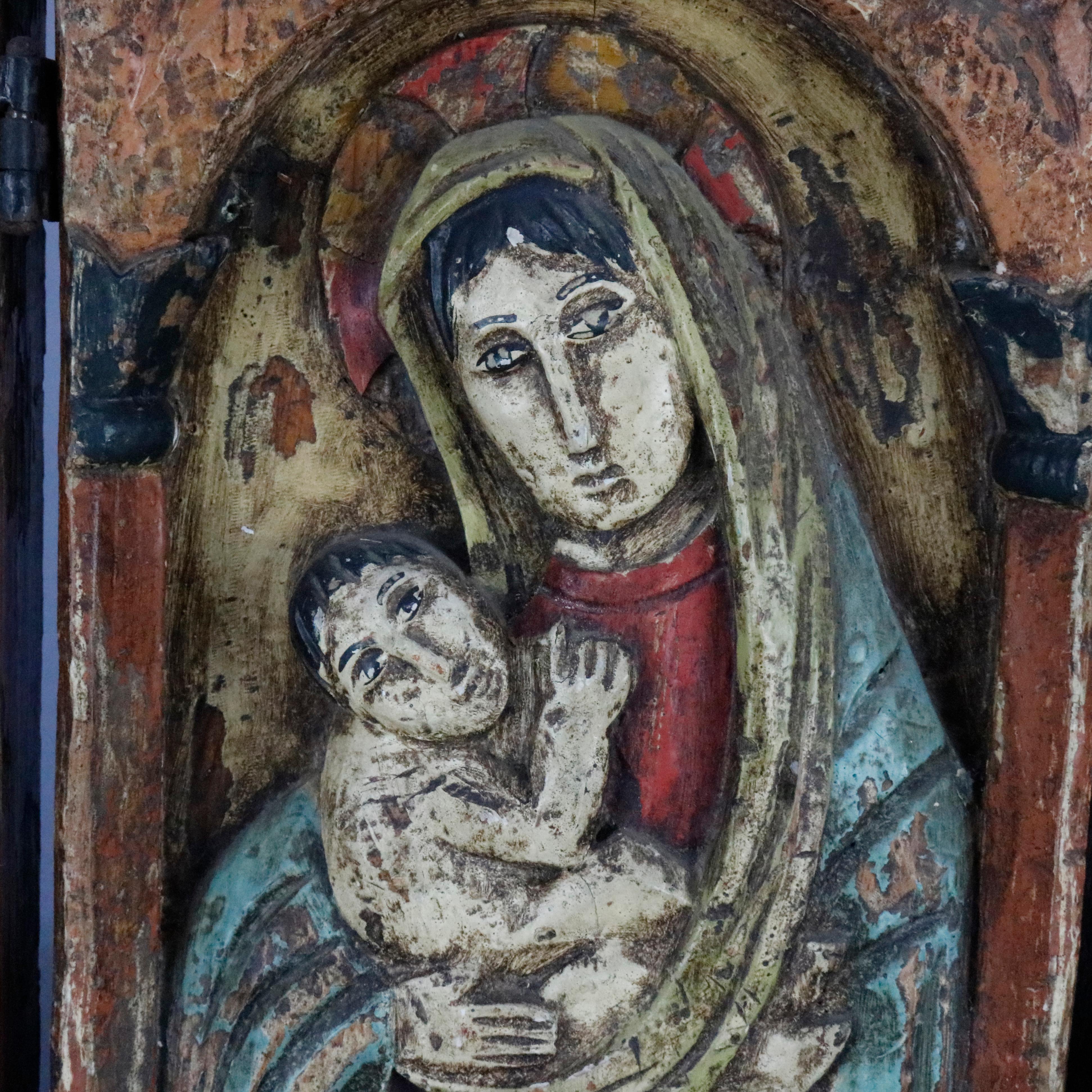 An antique Russian Orthodox icon offers triptych form with high relief and polychromed figures including central panel with Mother Mary and the Christ Child, folding with hand wrought iron hinges, circa 1700s.


Measures: 15.25