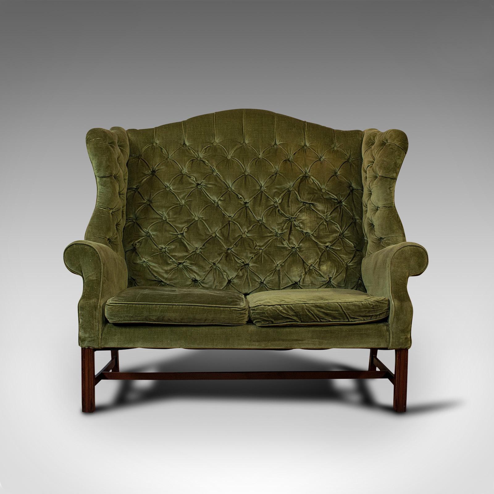 This is an antique high wing-back settee. An English, upholstered sofa or love seat over a beech frame, dating to the Edwardian period, circa 1910.

Inviting ivy green hues and attractive wing-back form
Displaying a desirable aged patina
Quality