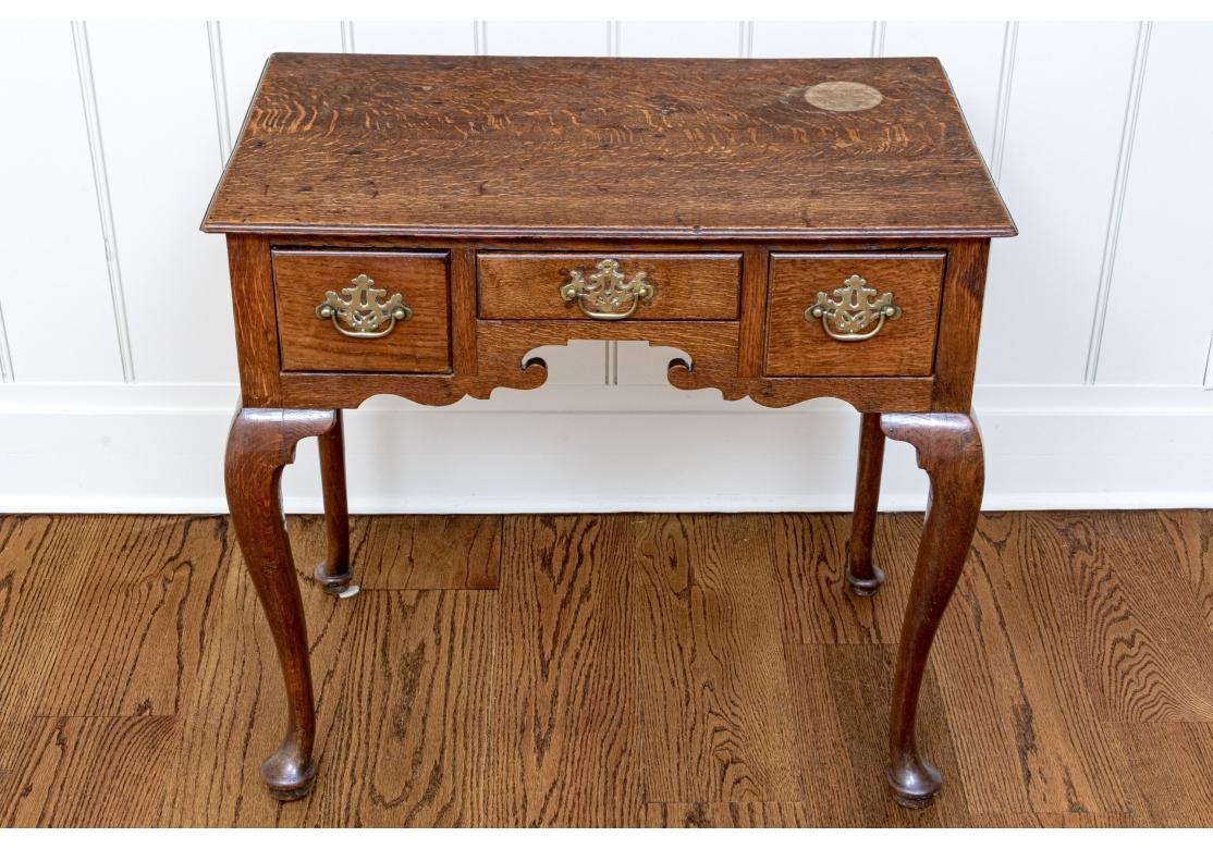 Lowboy du 18ème siècle de style Chippendale en chêne à grain fin, comprenant trois tiroirs avec des ferrures Batwing en laiton d'origine, un tablier festonné et de minces pieds cabriole se terminant par des pieds en coussinet.

Dimensions :  17 3/4