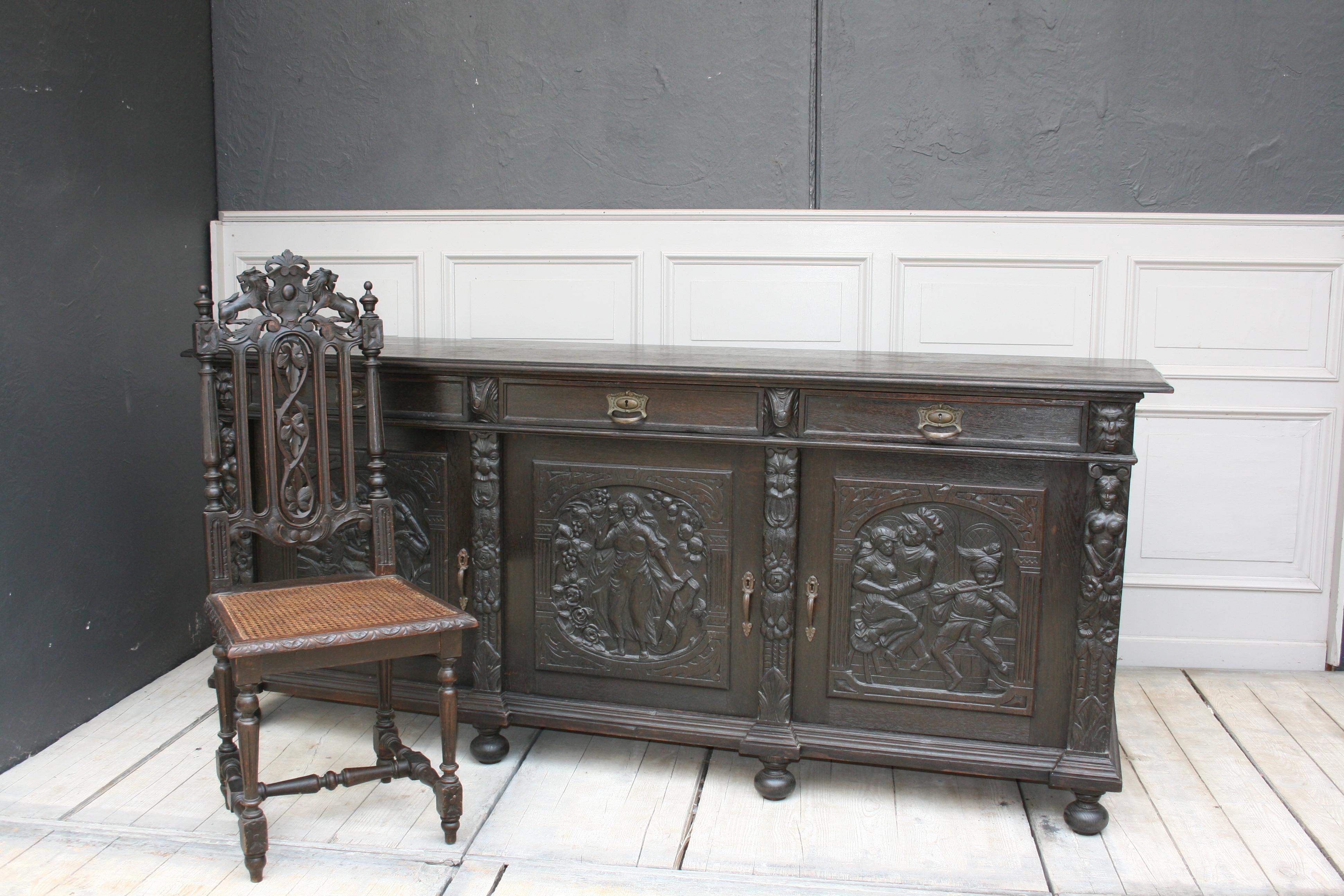 Antique black oak sideboard/credenza with 3 doors and 3 drawers. From the time of historicism, circa 1880. 
Original fittings and handles. Many carved ornaments, including scenes of drinking and dancing people or even grotesque grimaces. Origin: