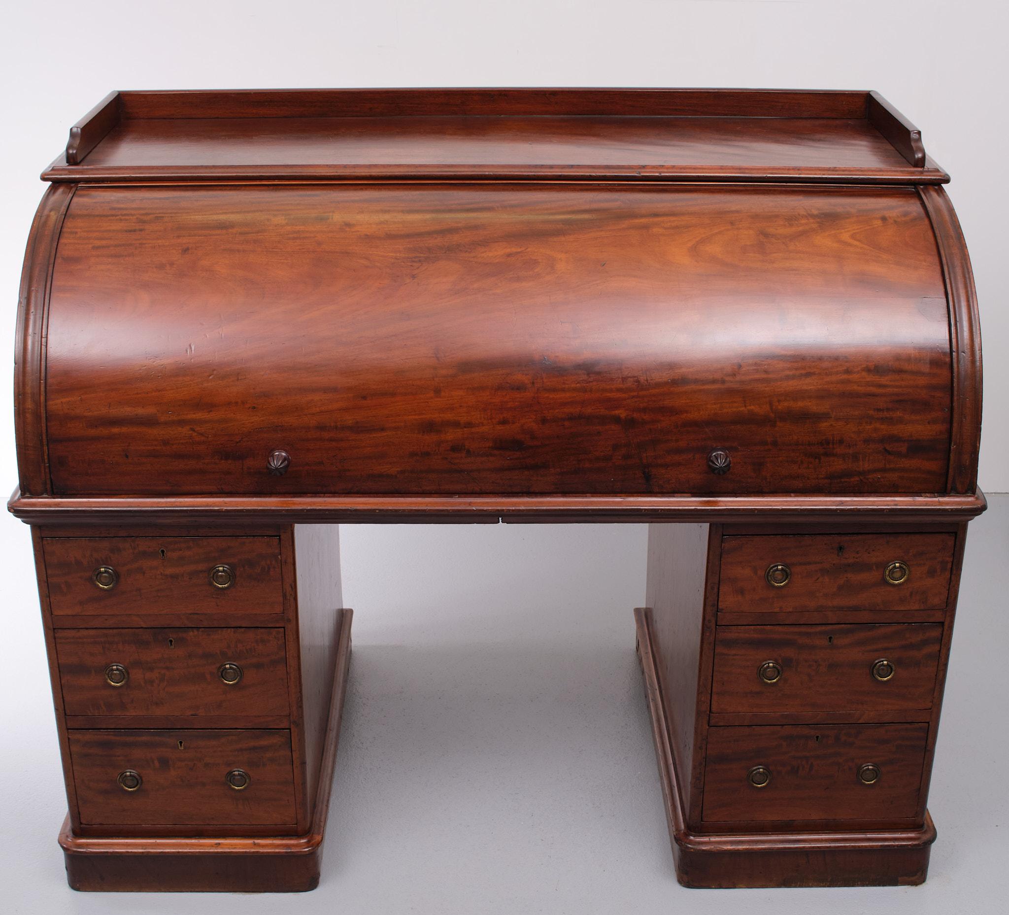 A truly outstanding piece of Victorian mahogany antique furniture this beautiful flamed mahogany cylinder desk features a small up stand to top, a large barrel fronted desk compartment, and a quality fitted interior. The inside of the desk features