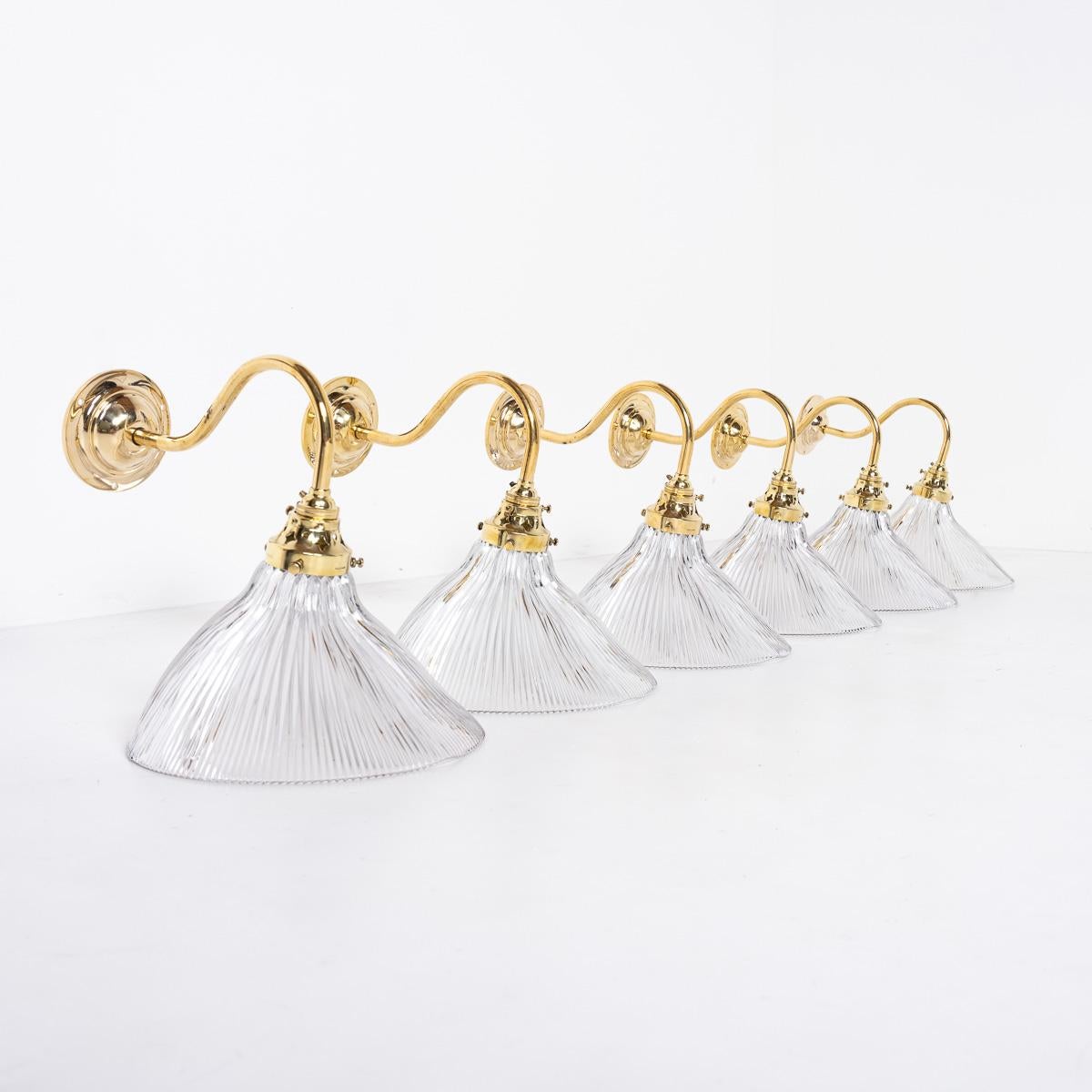 ANTIQUE ANGLED HOLOPHANE PRISMATIC GLASS WALL LIGHTS
PRICE IS PER LIGHT

An stunning run of antique Holophane prismatic glass lights with original aged brass fittings, swan neck wall brackets with heavy cast brass wall plates.

Fittings are all
