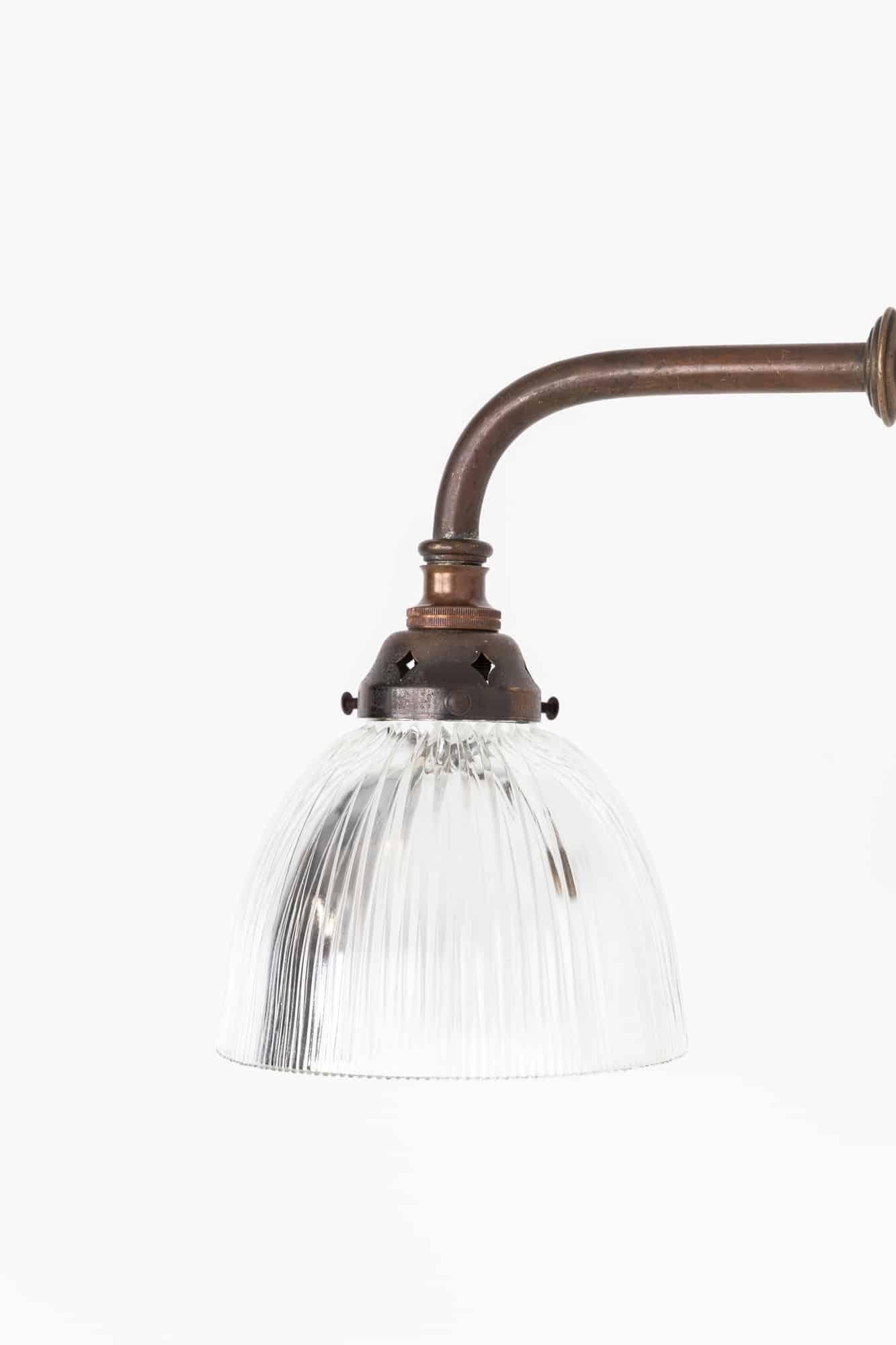 An incredibly elegant wall mounted light made in England by Holophane. c.1920

The simple prismatic glass shade made by Holophane, stamped to rim, and simple brass swan neck wall bracket with attractive patina and aging.