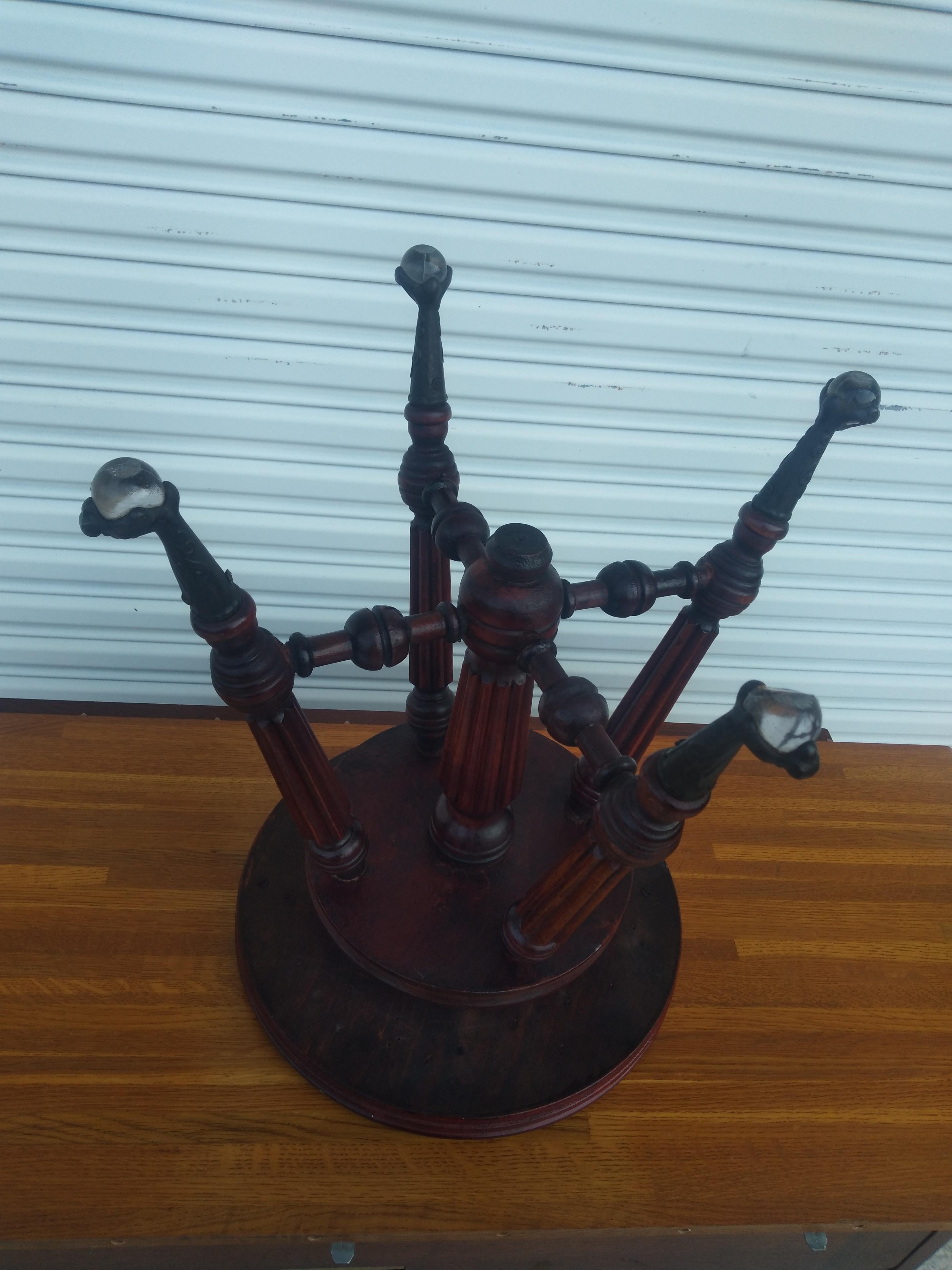 This piano stool is made by Holtzman and Sons. It's made of walnut and has a swivel adjustable seat. It adjust from 19' to 24' high. The legs are turned and end in metal claws clasping a glass ball.