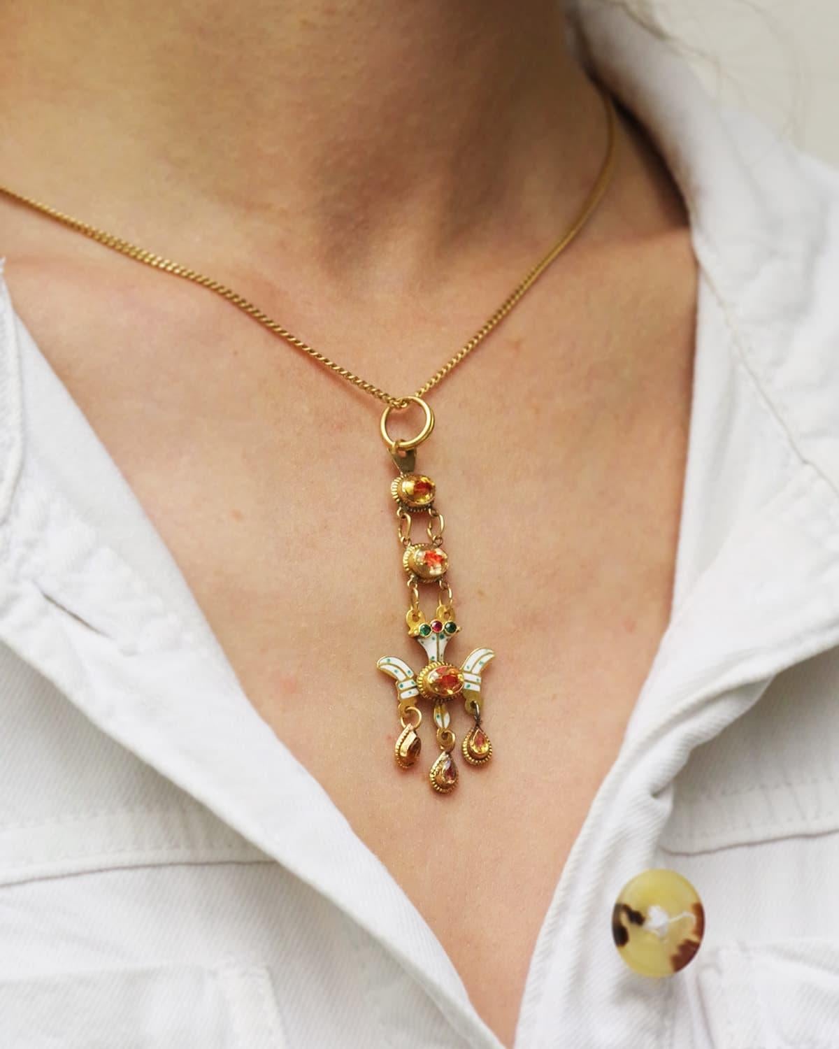 Antique Holy Spirit from Aurillac in 18 karat gold. Antique regional Saint-Esprit d'Aurillac pendant, set with citrines on red paillon, ending with a stylized dove enameled with green dots on a white background, holding three citrines as pendants.