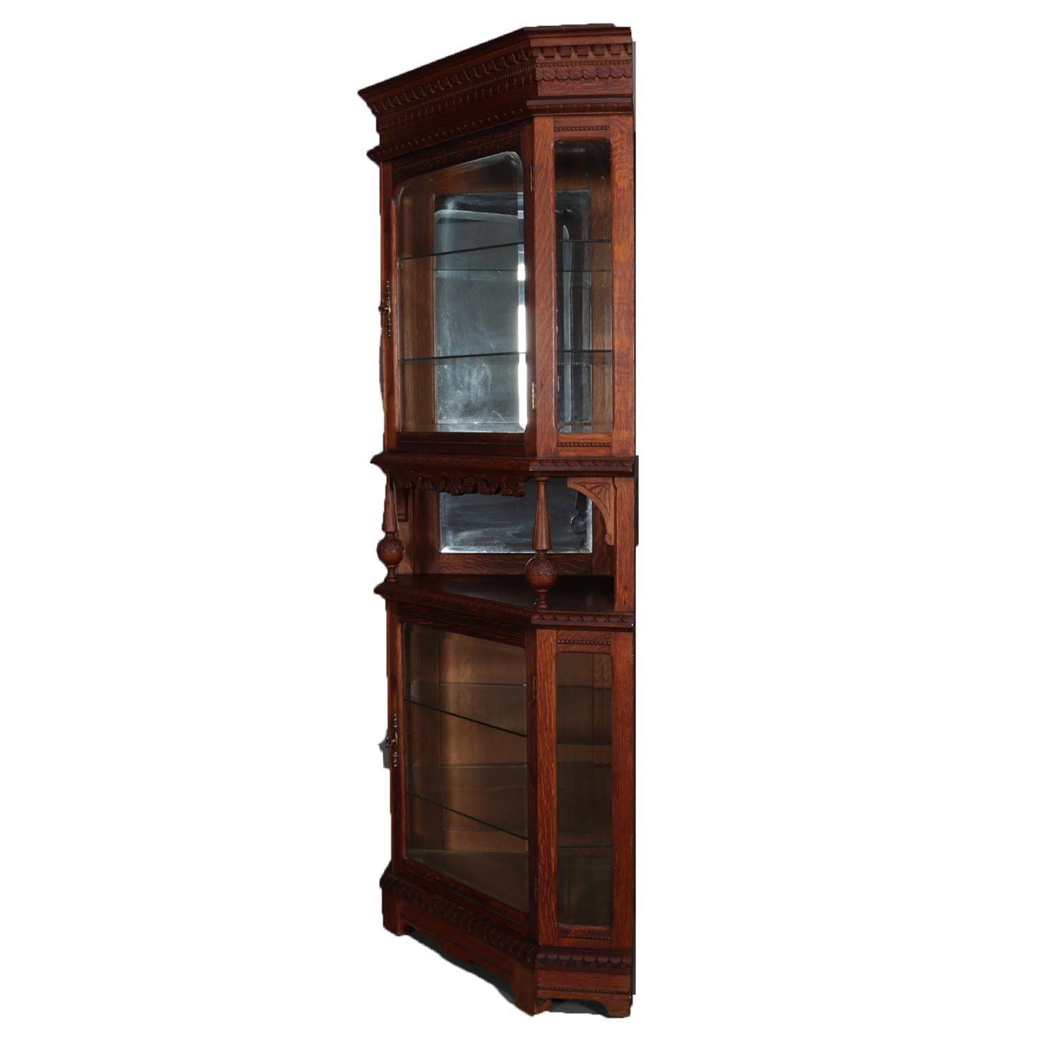 An antique Horner School corner cabinet features faceted form with oak construction having glass enclosed upper with mirrored interior and glass shelves and having carved floral and foliate skirting surmounting open and mirrored centre display over