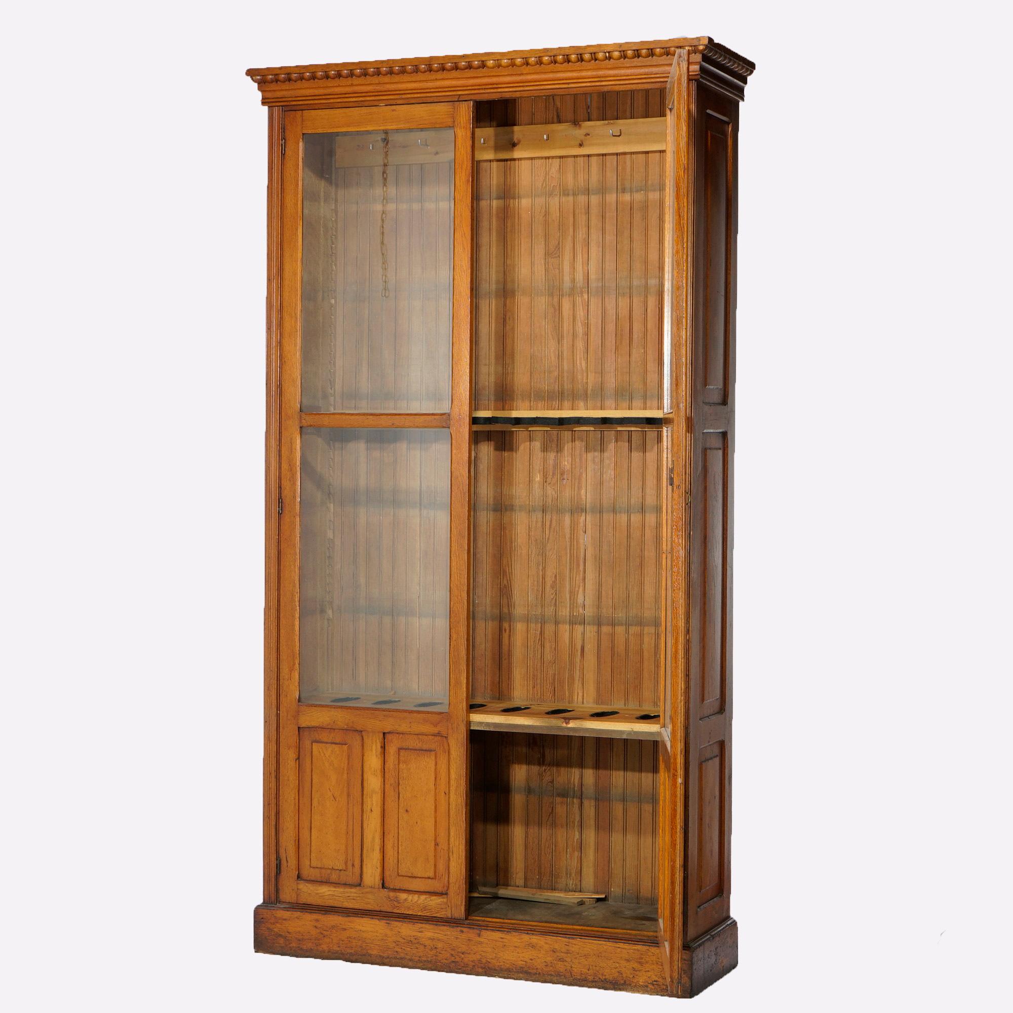 An antique gun cabinet in the manner of Horner offers paneled oak construction with double glass doors over blind door storage area, c1900

Measures- 94.25''H x 51.25''W x 16''D.