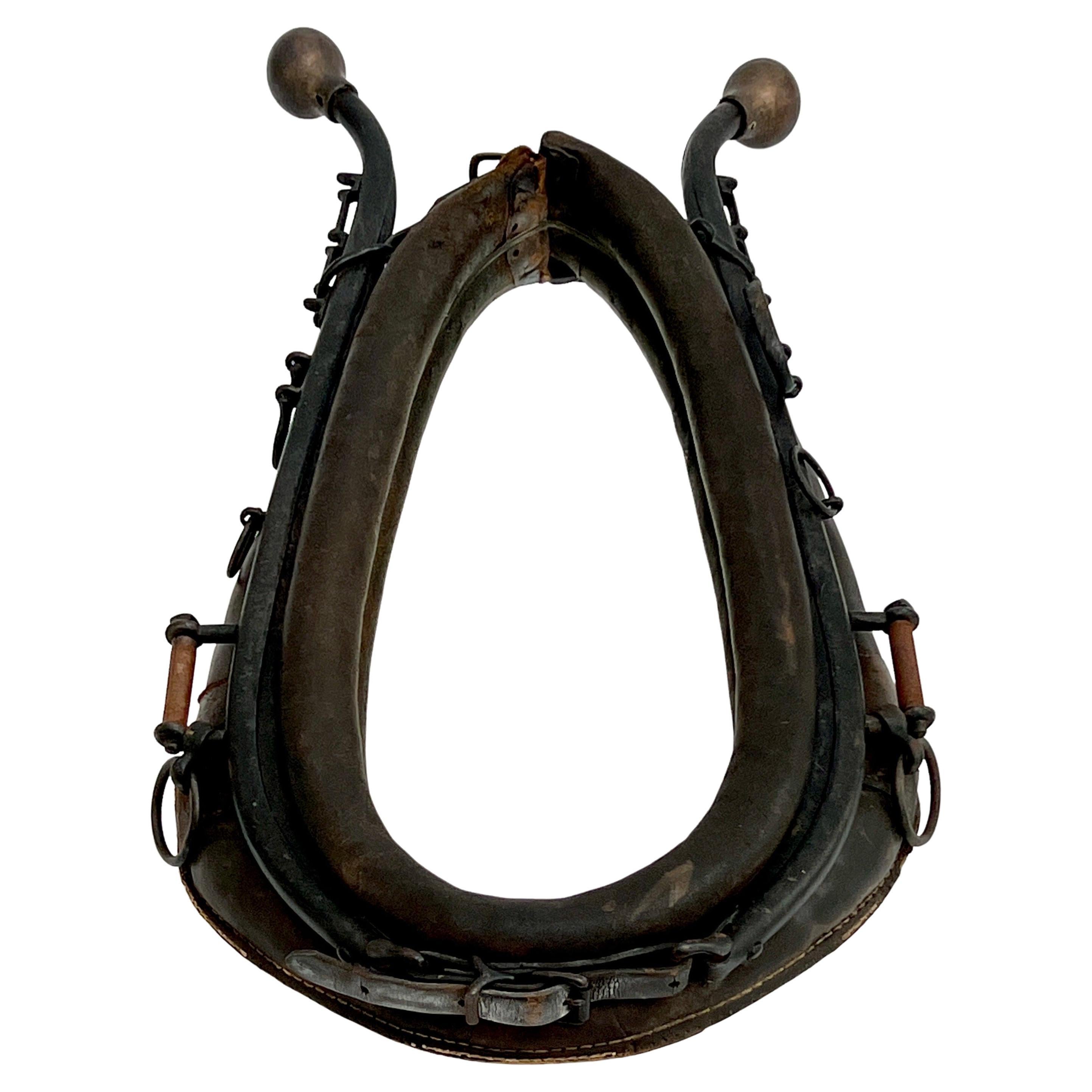 Antique horse collar mirror from the late 19th Century.  Features distressed black leather collar with iron hames in black enamel fitted with patinated brass ball finials, and iron rings along the sides.  Originally used as a horse harness.  