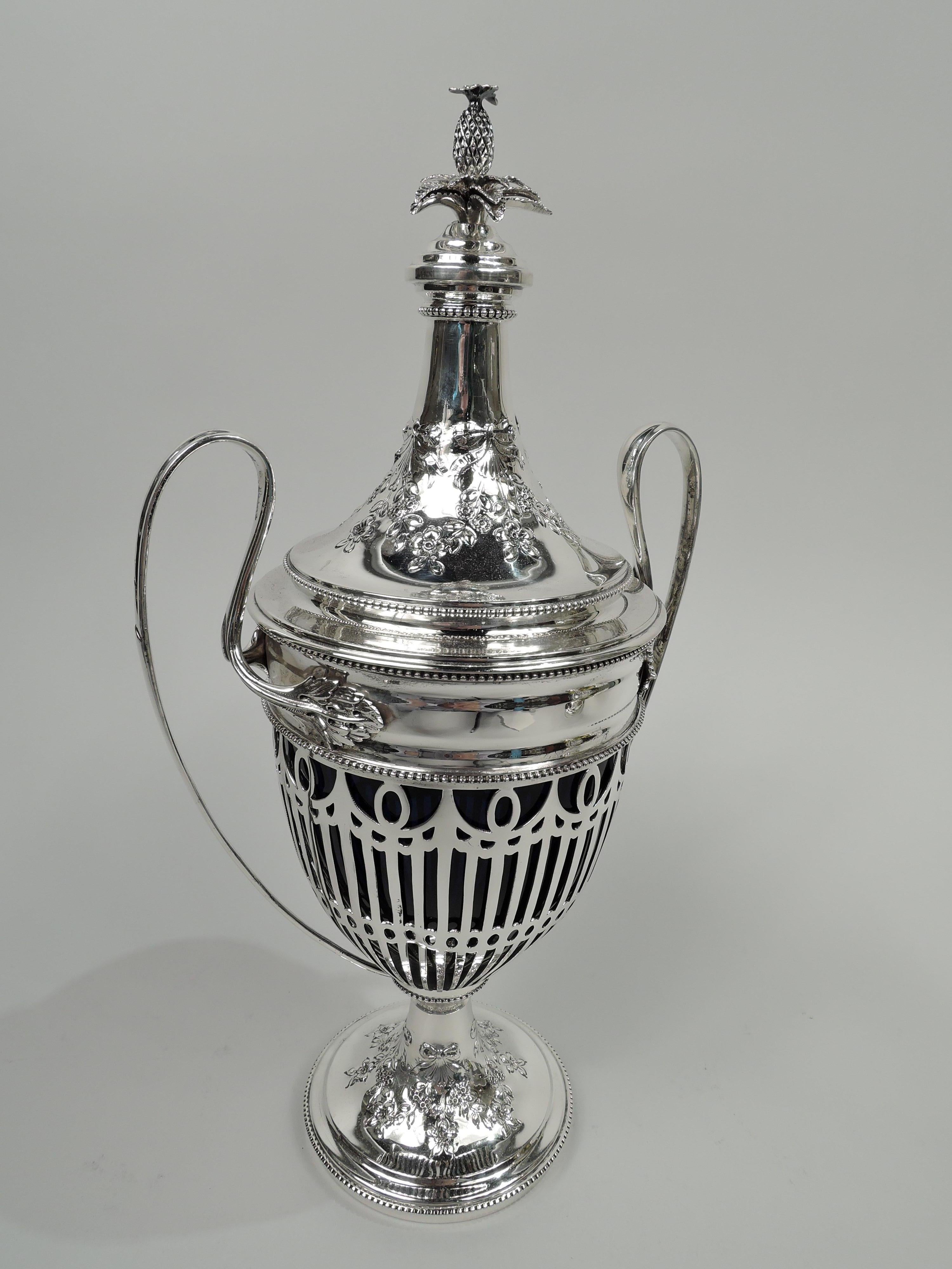 Edwardian neoclassical sterling silver covered urn. Made by Howard & Co. in New York in 1905. Ovoid bowl with high-looping leaf-mounted side handles; domed foot. Cover domed; top stepped with cast pineapple finial. Sides open with flutes and
