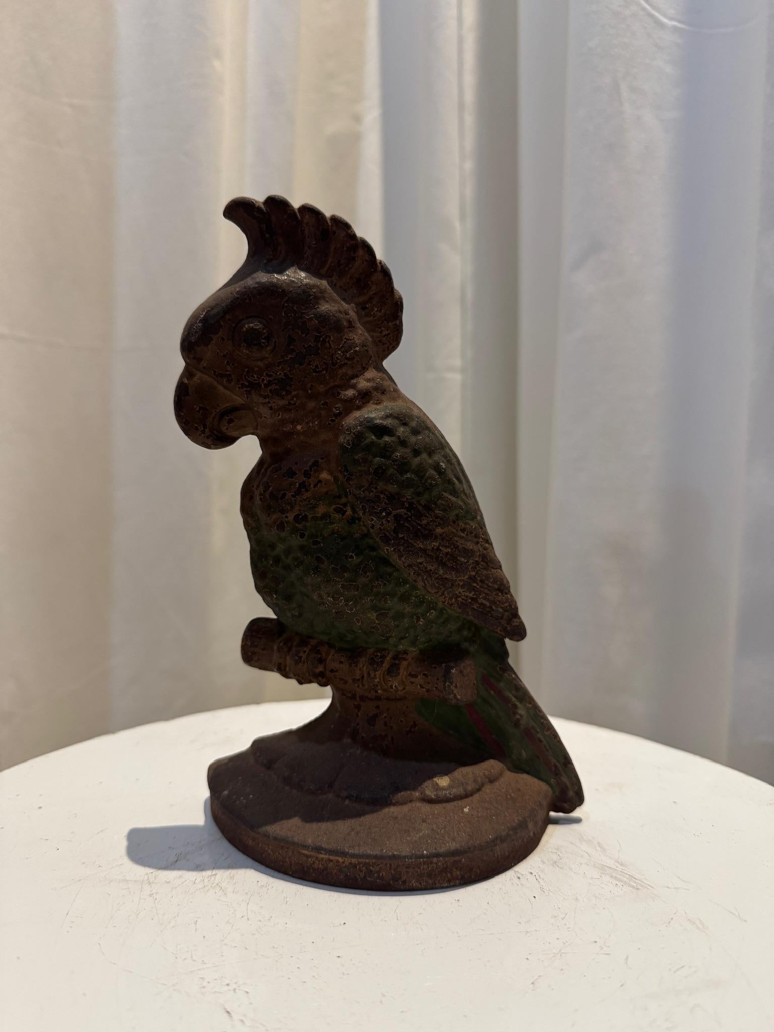 This rare antique Hubley cast iron parrot doorstop is a stunning example of early 20th-century craftsmanship. Featuring a beautifully sculpted parrot perched on a branch, this piece showcases vibrant hand-painted details in shades of green, red, and