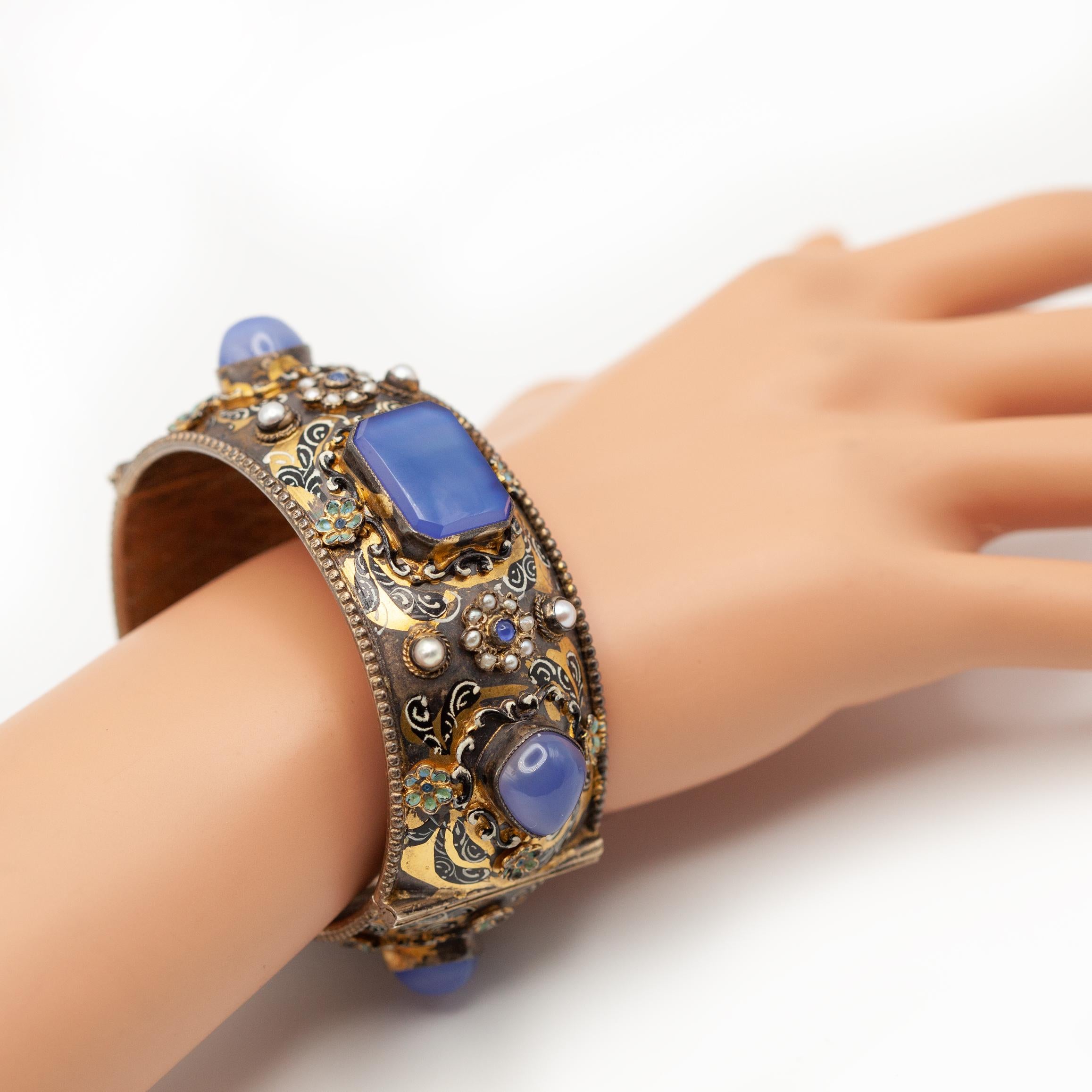 Magnifique exemple de l'artisanat austro-hongrois, ce rare bracelet antique en vermeil datant des années 1900. Le large bracelet à charnière est orné d'un exquis émail peint à la main en riches motifs floraux et feuillus polychromes, rehaussés d'une