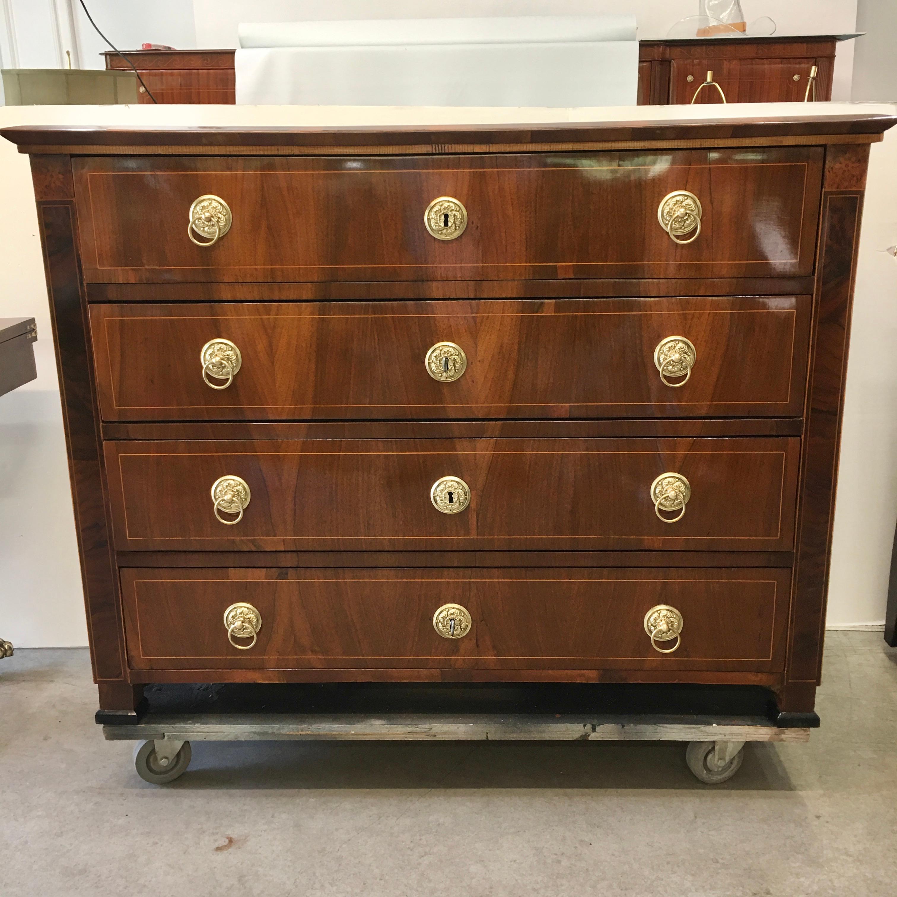 Antique Hungarian chest of drawers from around 1840. Walnut veneer over a pine structure with poplar and hardwood inlay, four deep drawers each with gilded cast copper ring pulls and with original locks, plus two keys.