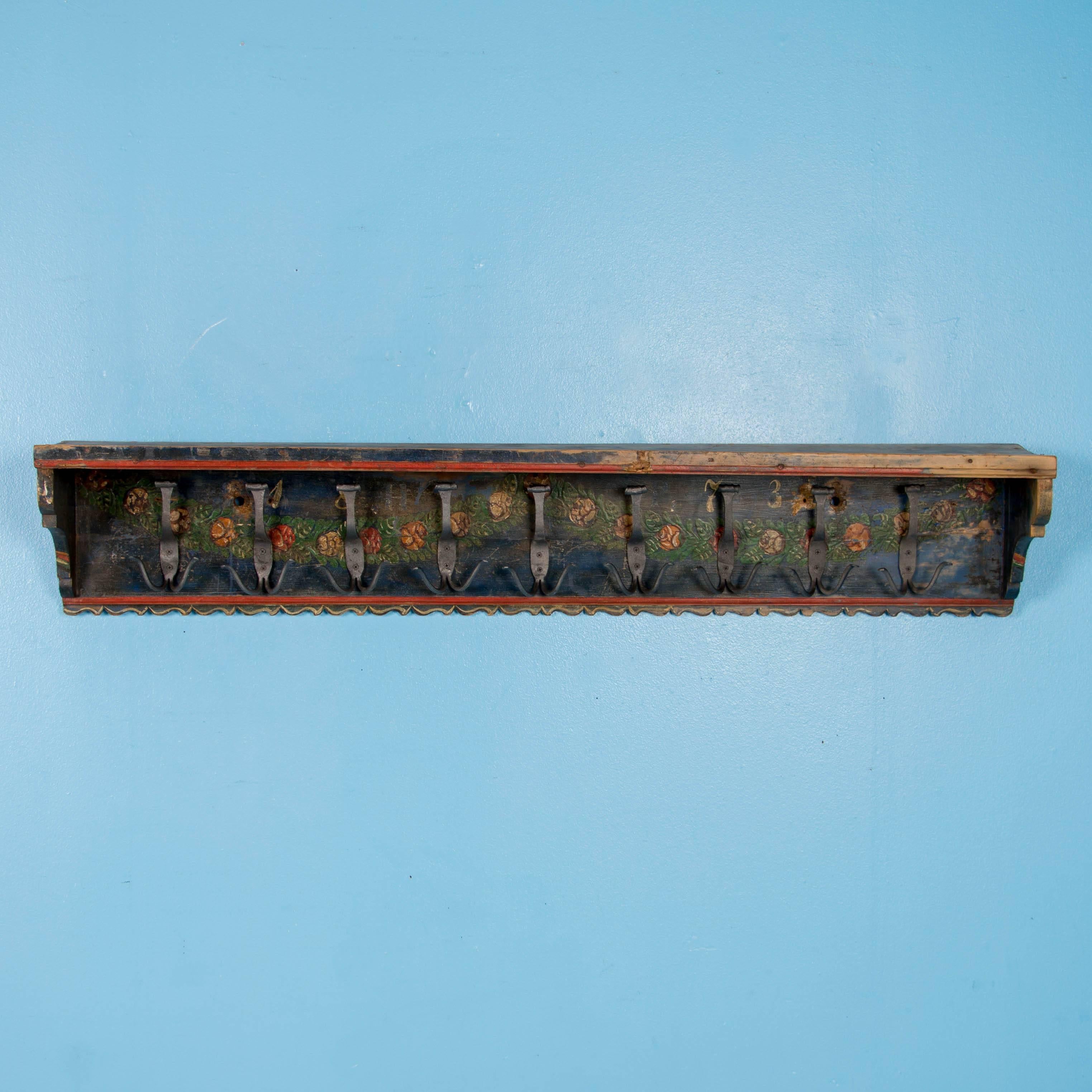 This delightful hanging shelf/rack still maintains its original floral Folk Art paint in reds and yellow over a blue colored background with date of 1873. ?Painted racks with a shelf above and multiple hooks were common elements in a European