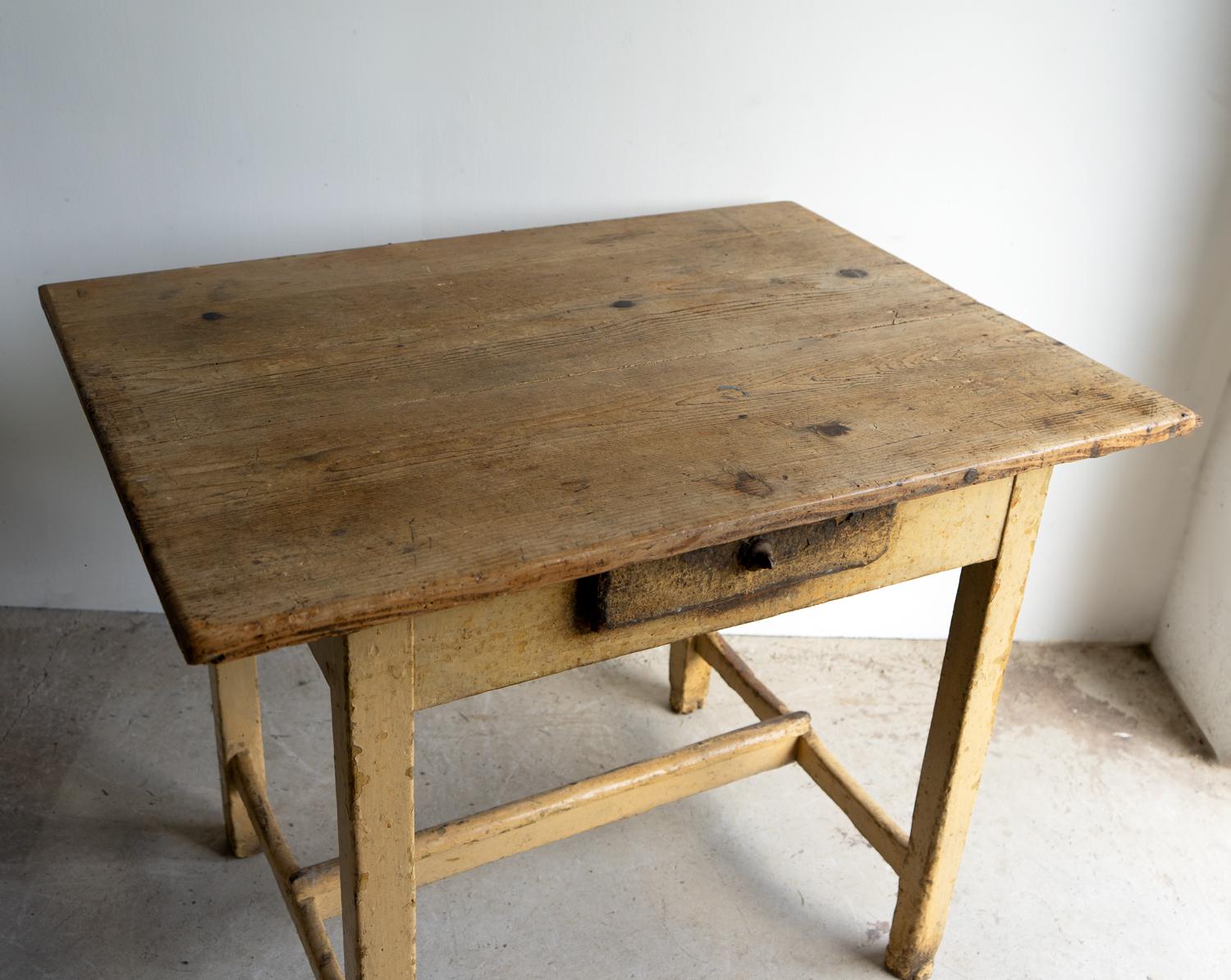 ANTIQUE SIDE TABLE

A decorative and rustic piece constructed of pine with square tapered legs united by an H-stretcher with a frieze drawer and a two-plank top.

Layers of original paint, the top layer being a buttery, creamy yellow, which has worn