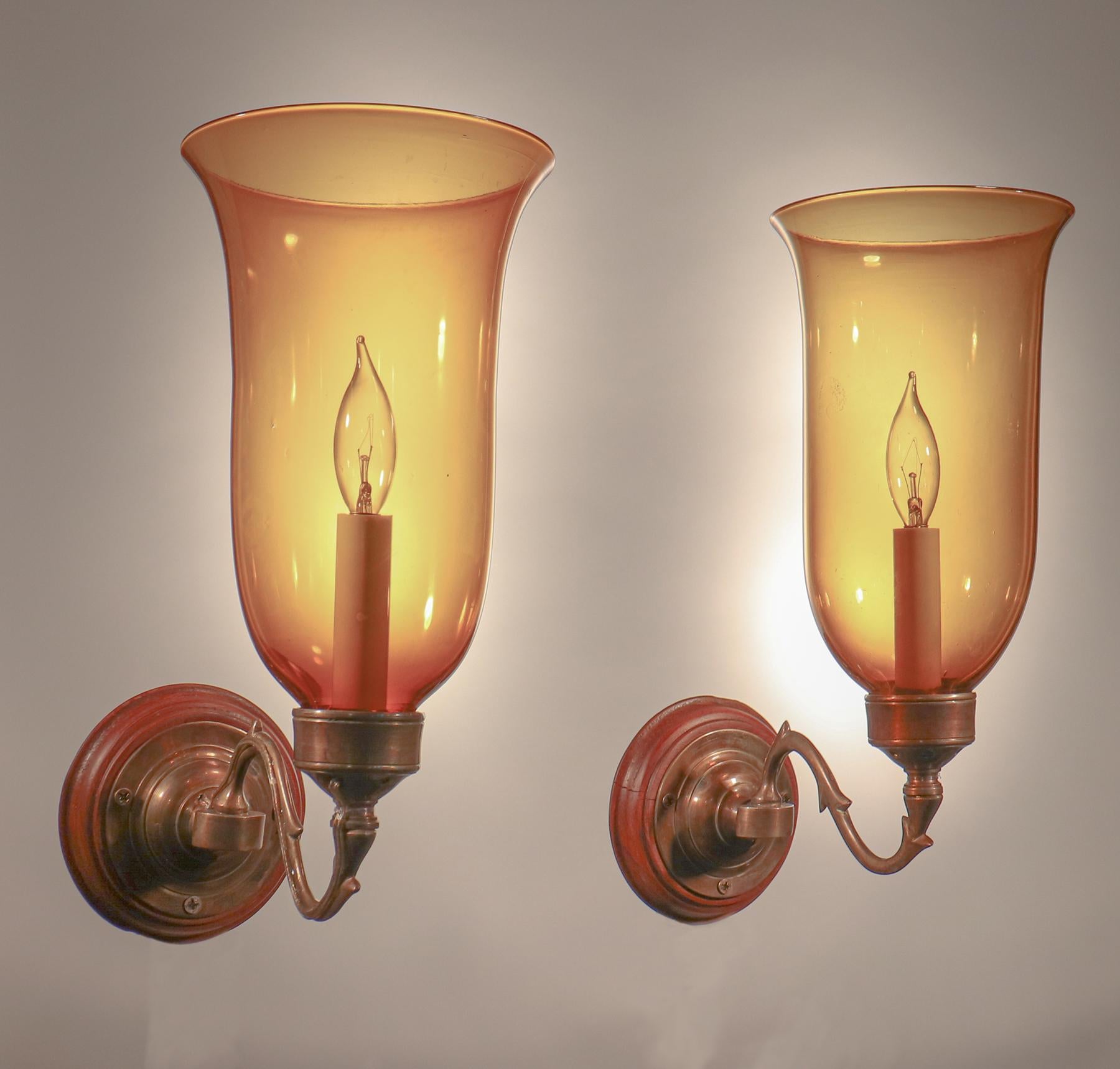 A beautiful pair of circa 1900 English hurricane shades with very good quality amber-colored hand blown glass and a flared form. Originally for candles, the wall sconces have been newly electrified, each with a single candelabra bulb.