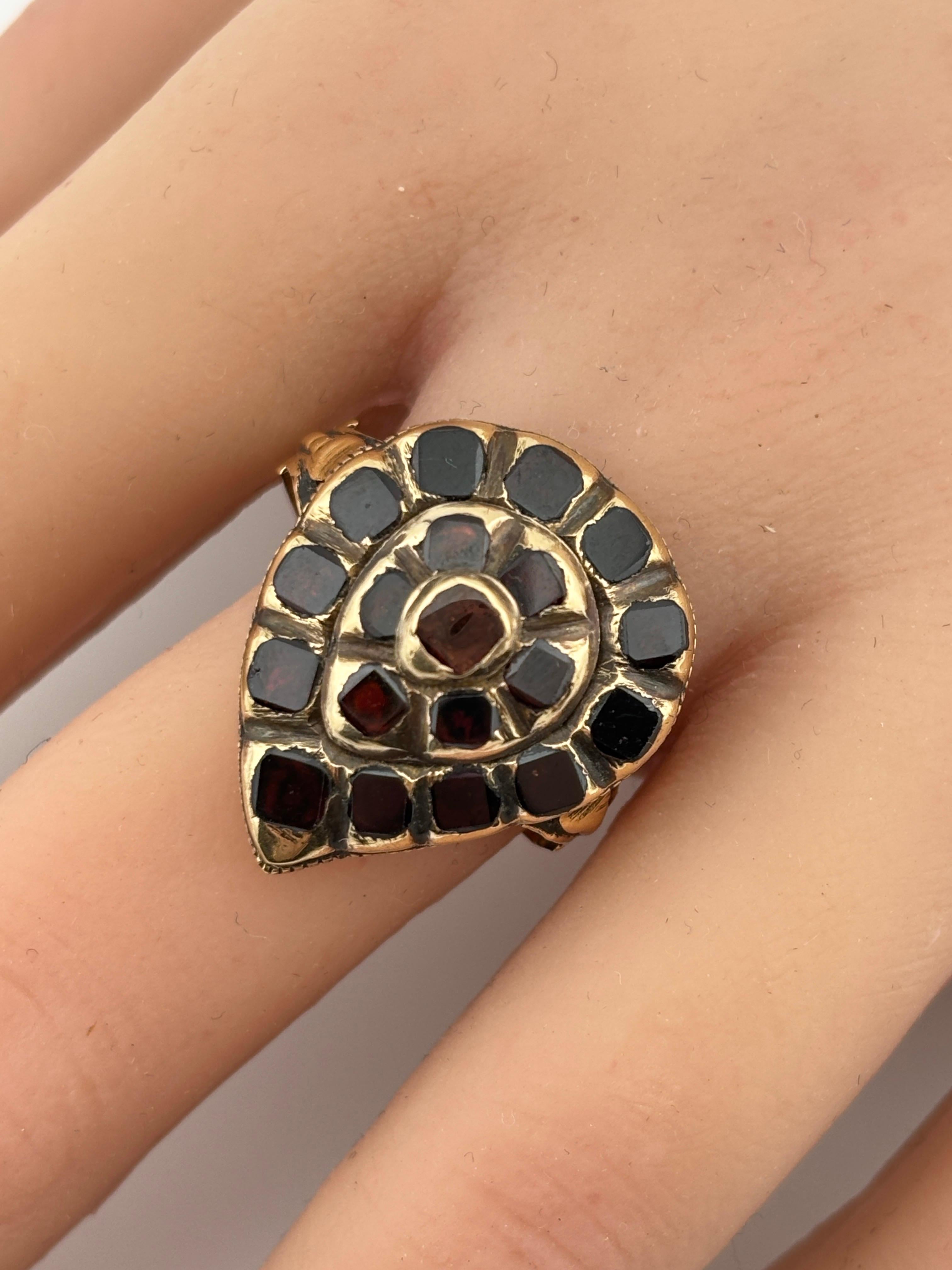 Il granato di questo anello è tagliato in stile table cut, un taglio molto diffuso nel XVIII secolo. Questo particolare taglio presenta una parte superiore piatta e larga con una superficie sfaccettata che conferisce alla pietra una sottile